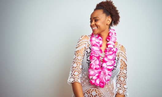 African American woman wearing a flower Hawaiian lei smiling because her skin is benefiting from kukui nut oil products.