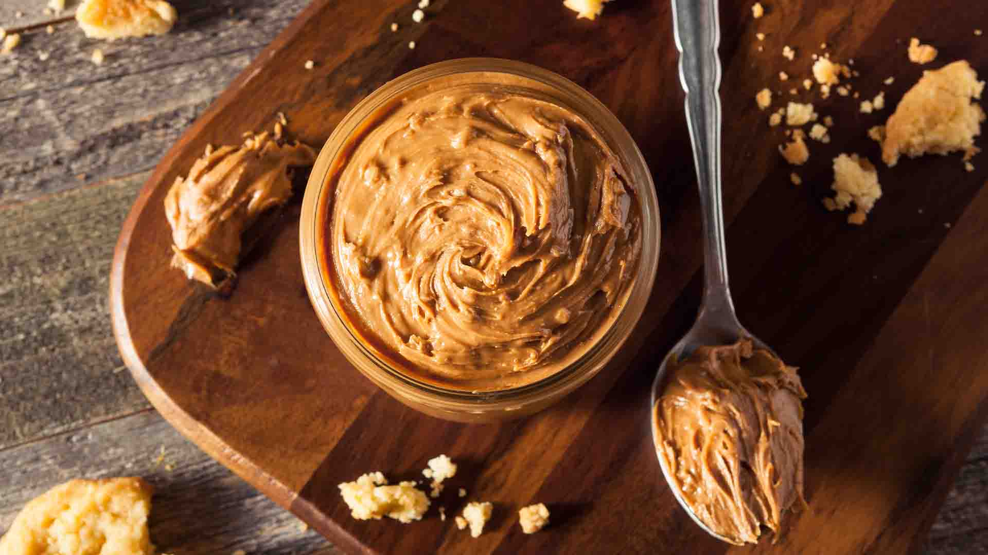 Small bowl of chunky peanut butter and a spoonful of peanut butter