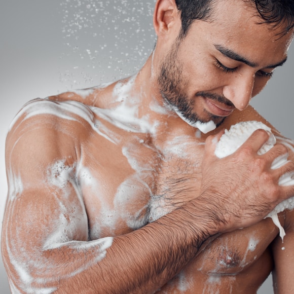 Young man lathering up in the shower with body wash that fights odor and sweat control