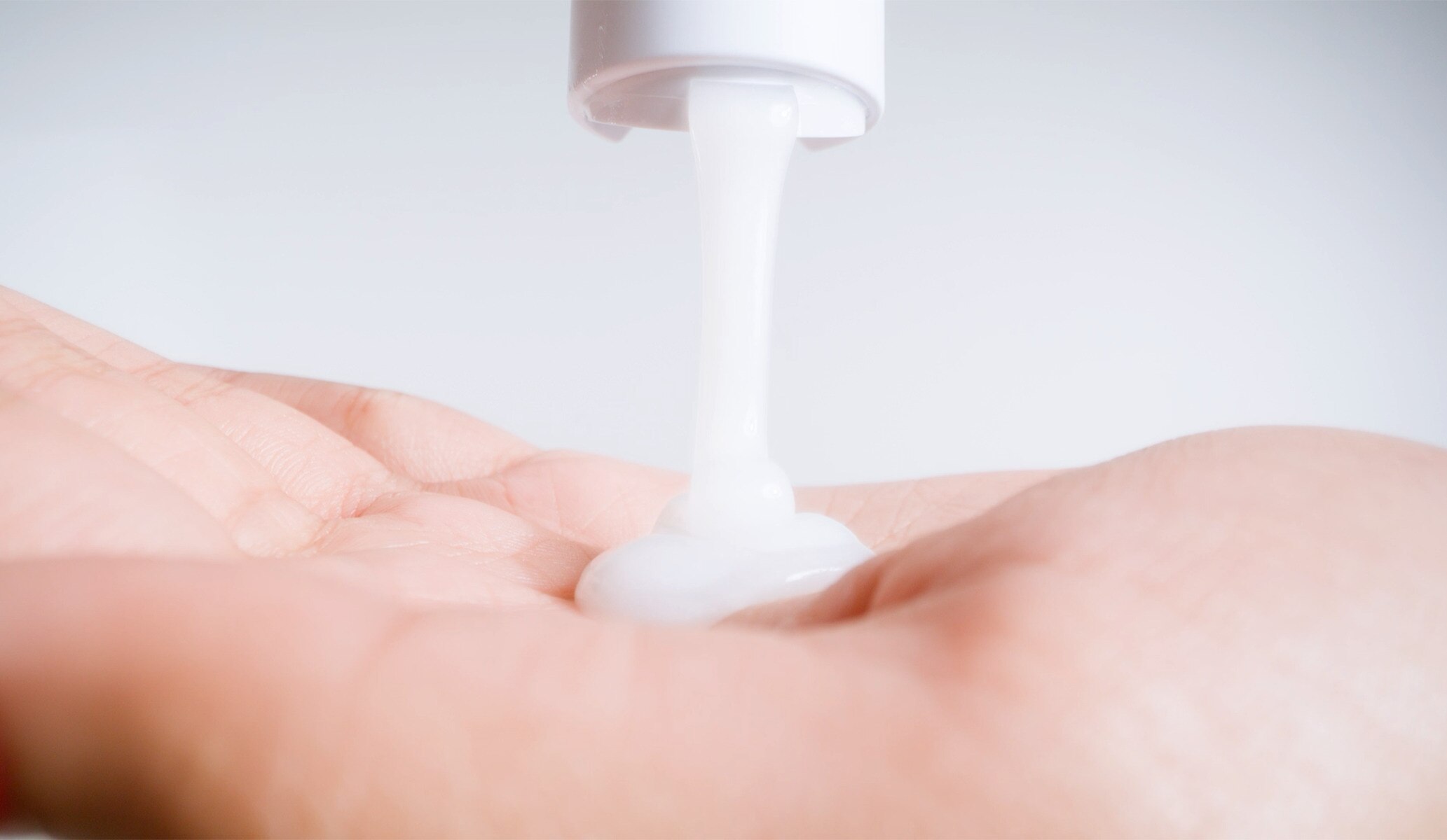 Close-up image of a person pouring a shampoo product into their hand