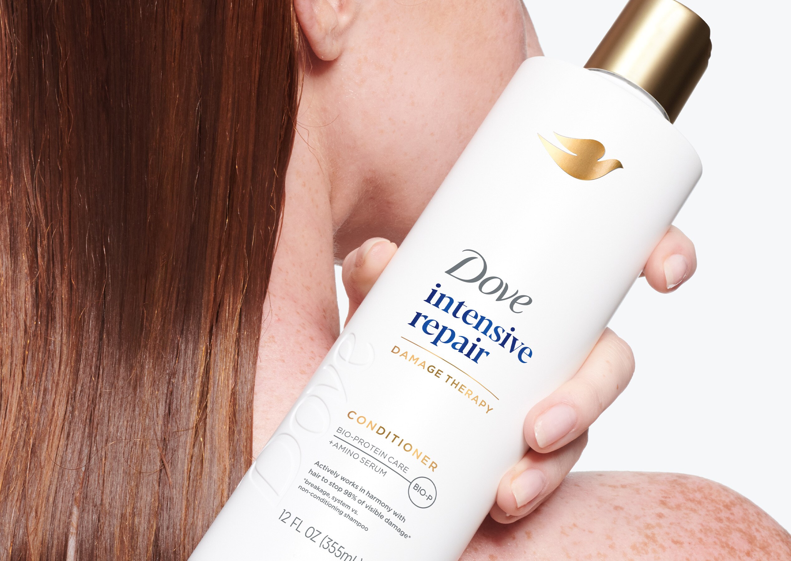 Woman holding Dove Intensive Repair Conditioner over her shoulder