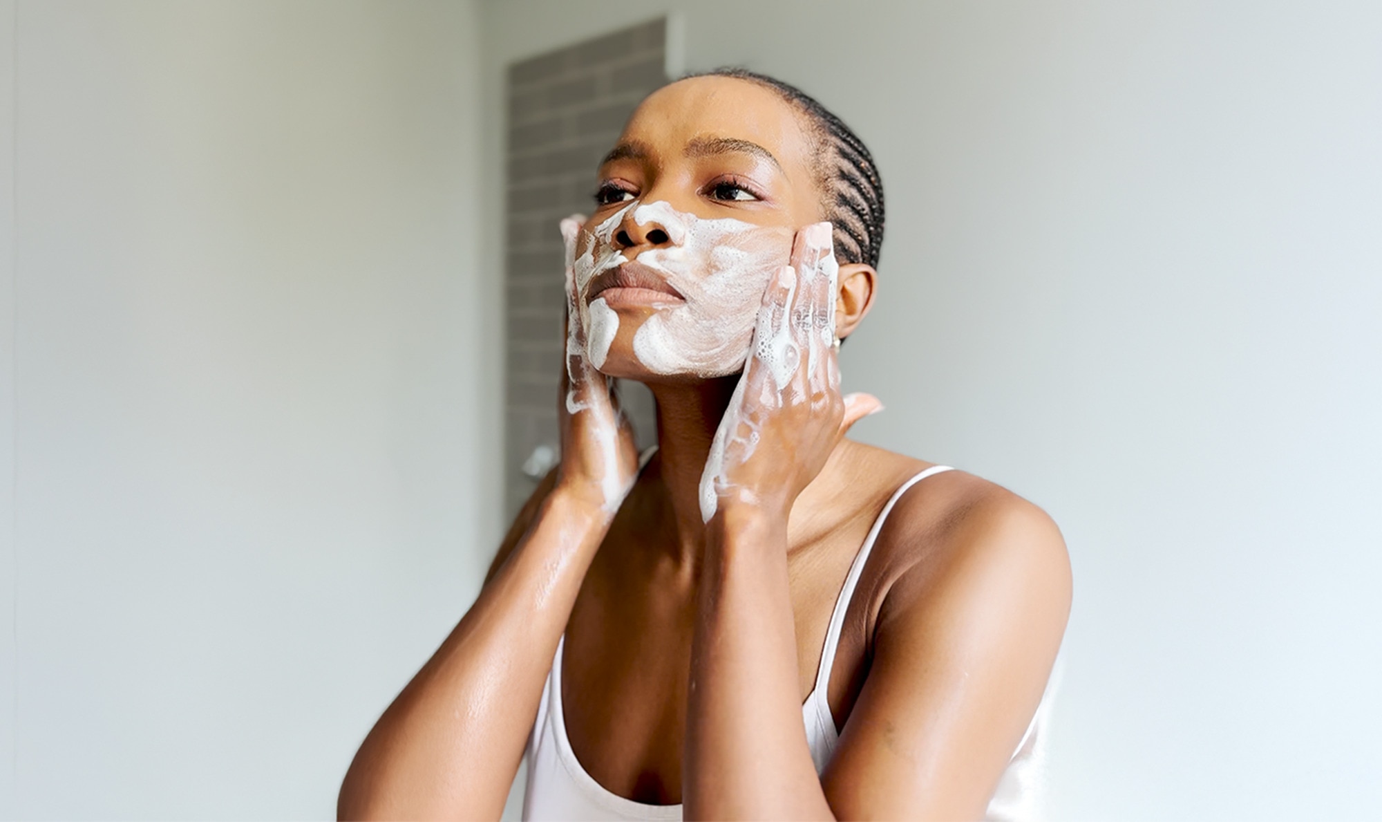 Woman lathering her face with foamy product