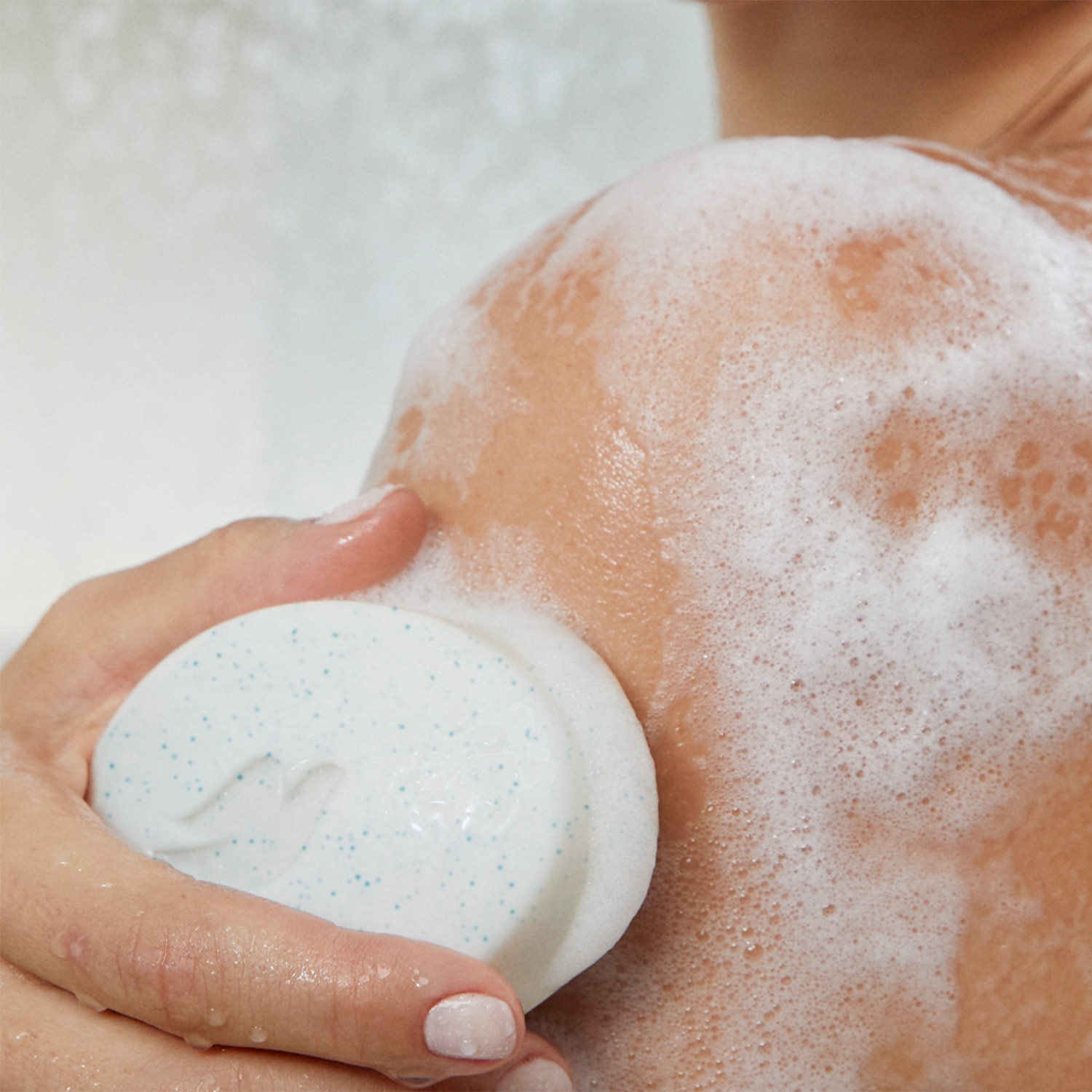 Hand lathering up a Dove Beauty Bar on a shoulder