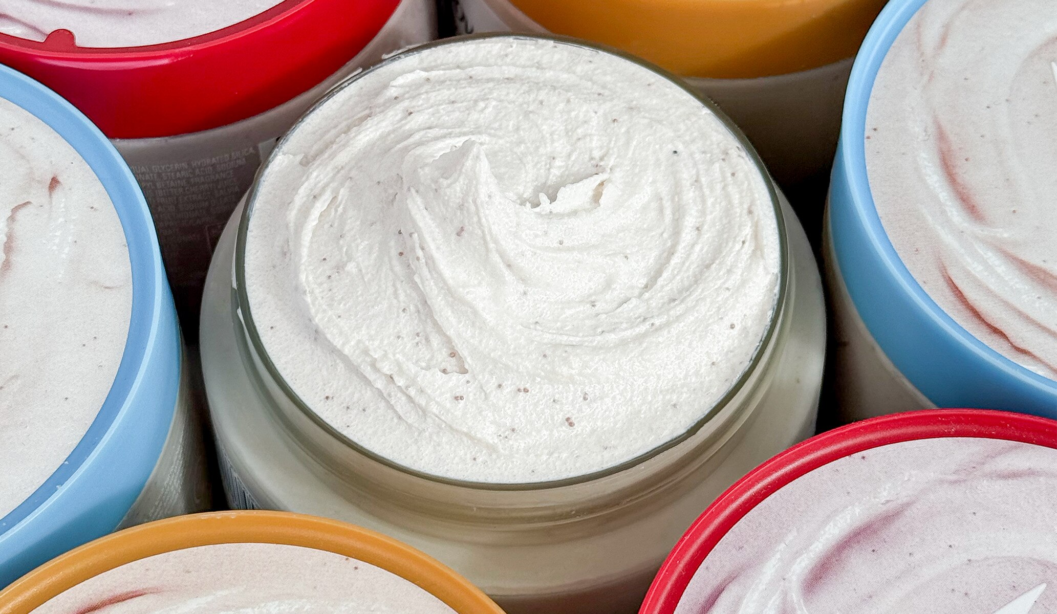 Close up of open-topped Dove body scrub tubs showing product texture inside