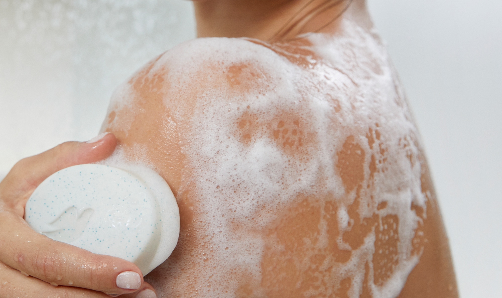 Hand lathering up a Dove Beauty Bar on a shoulder