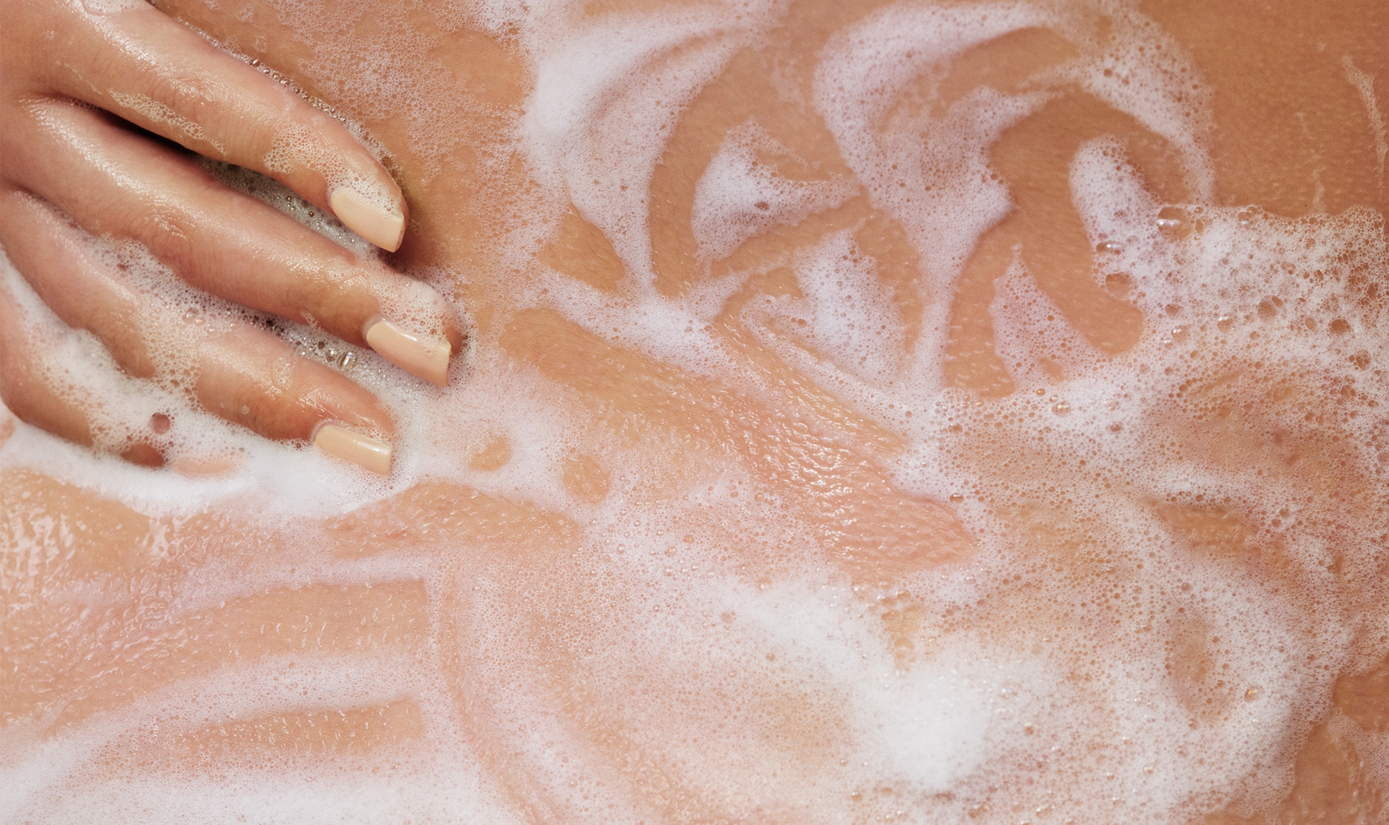 Hand lathering up foamy Dove Body Wash on a shoulder