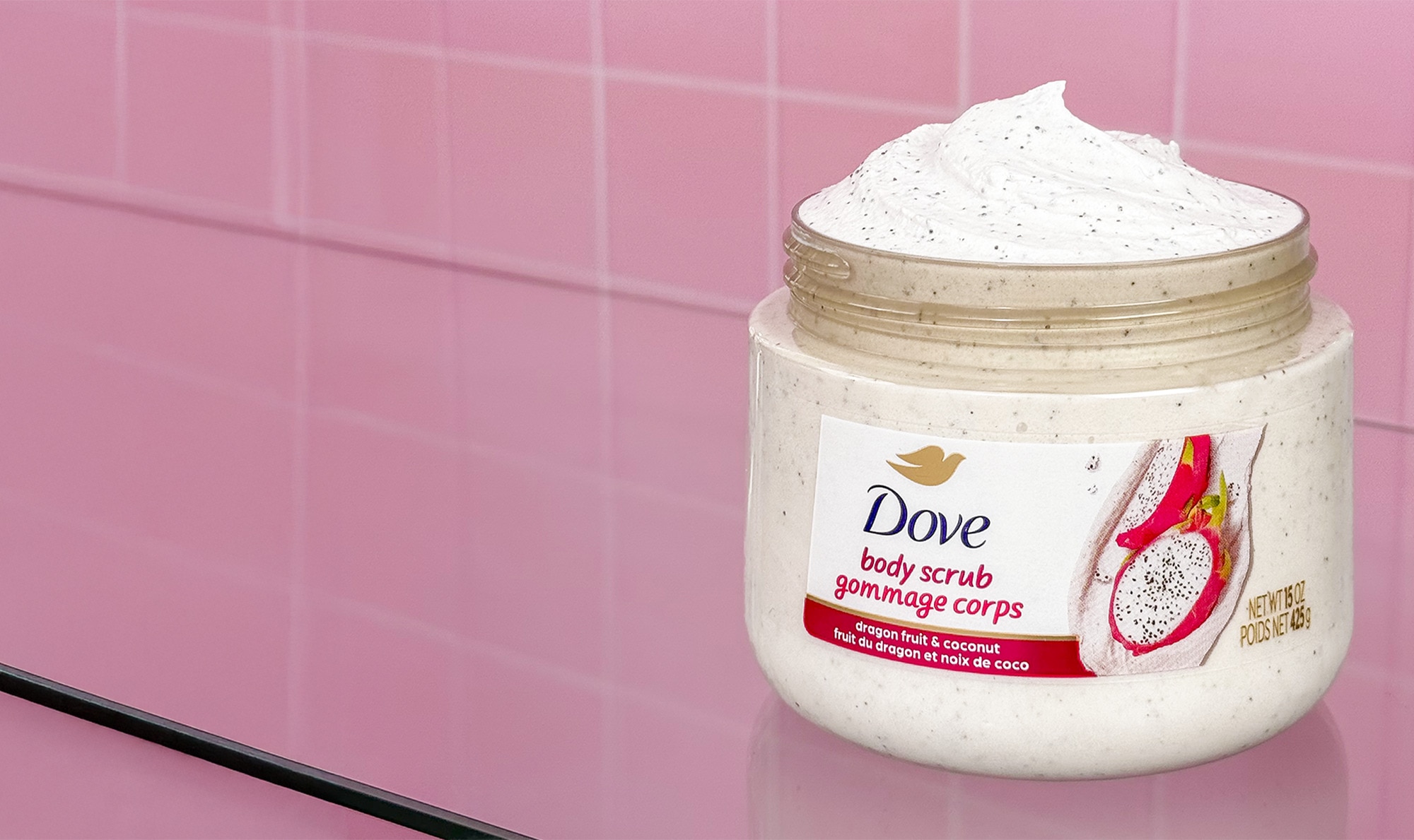 Dove body scrub tub with product against a pink bathroom tile backdrop