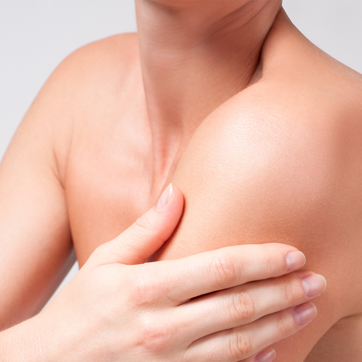 Woman rubbing moisturizer product onto their shoulder