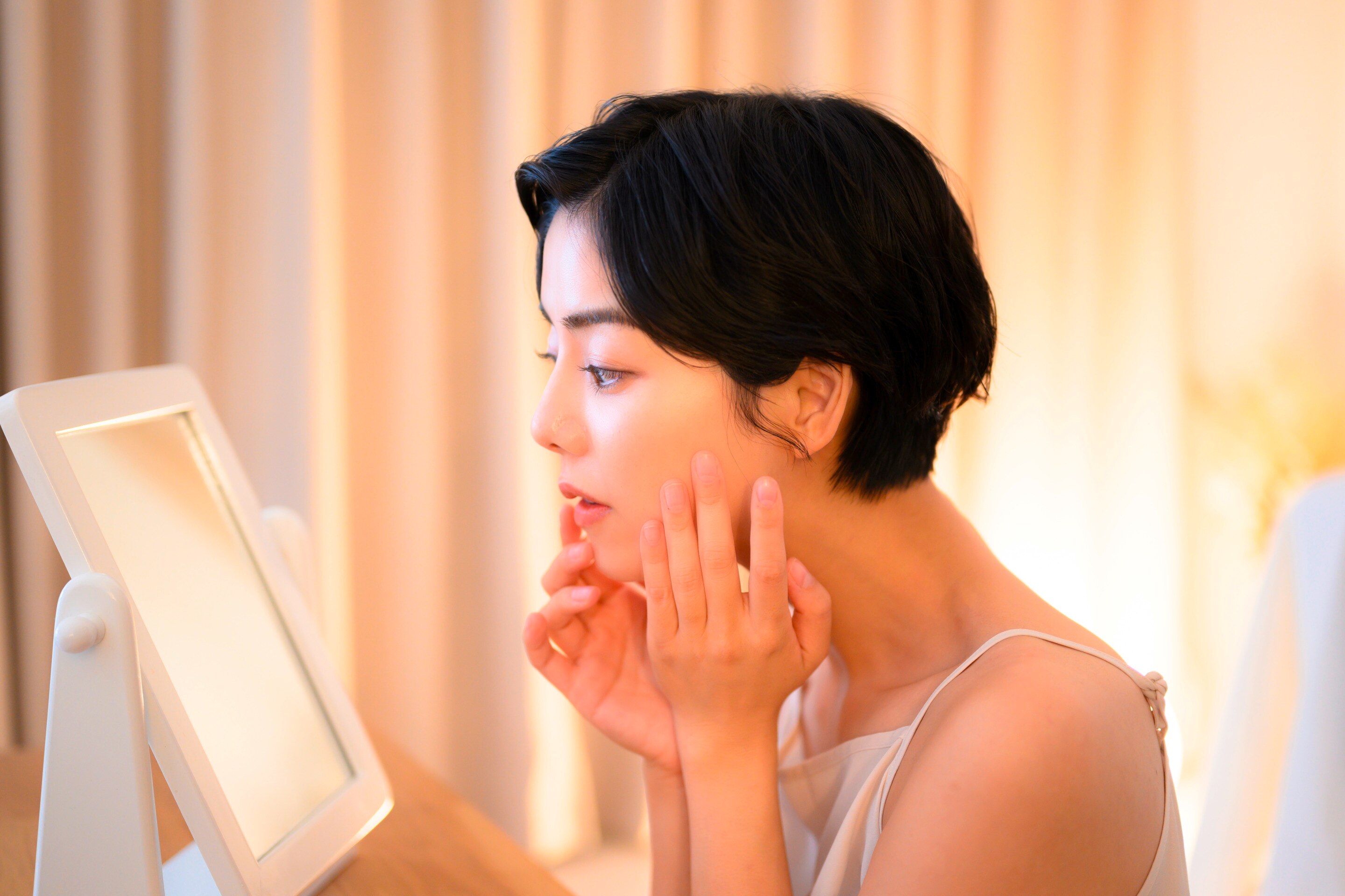 Woman applying skincare products on her face.