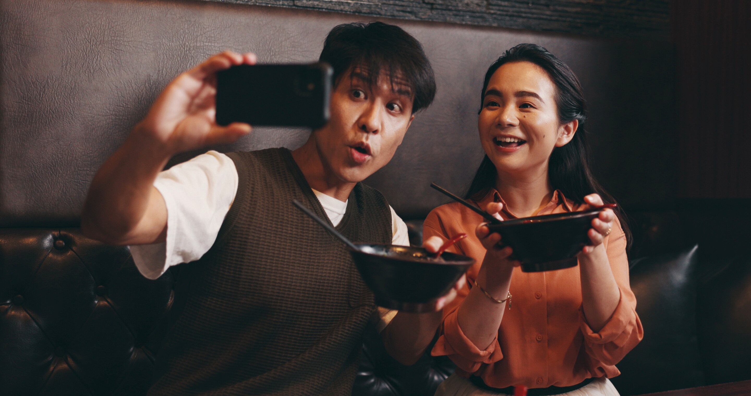 Asian couple taking a couple selfie during a meal.