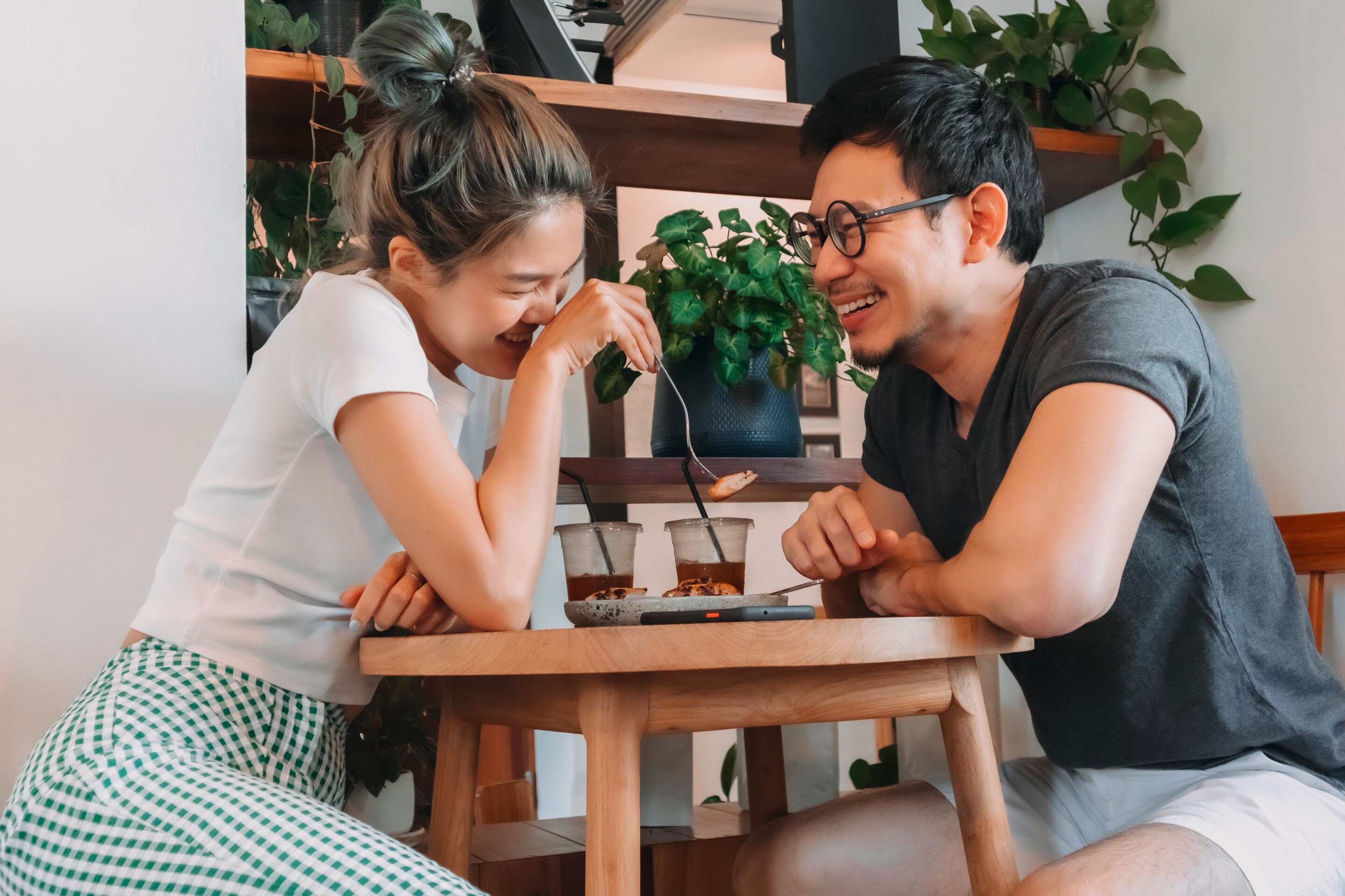 Asian couple laughing and enjoying a meal together.