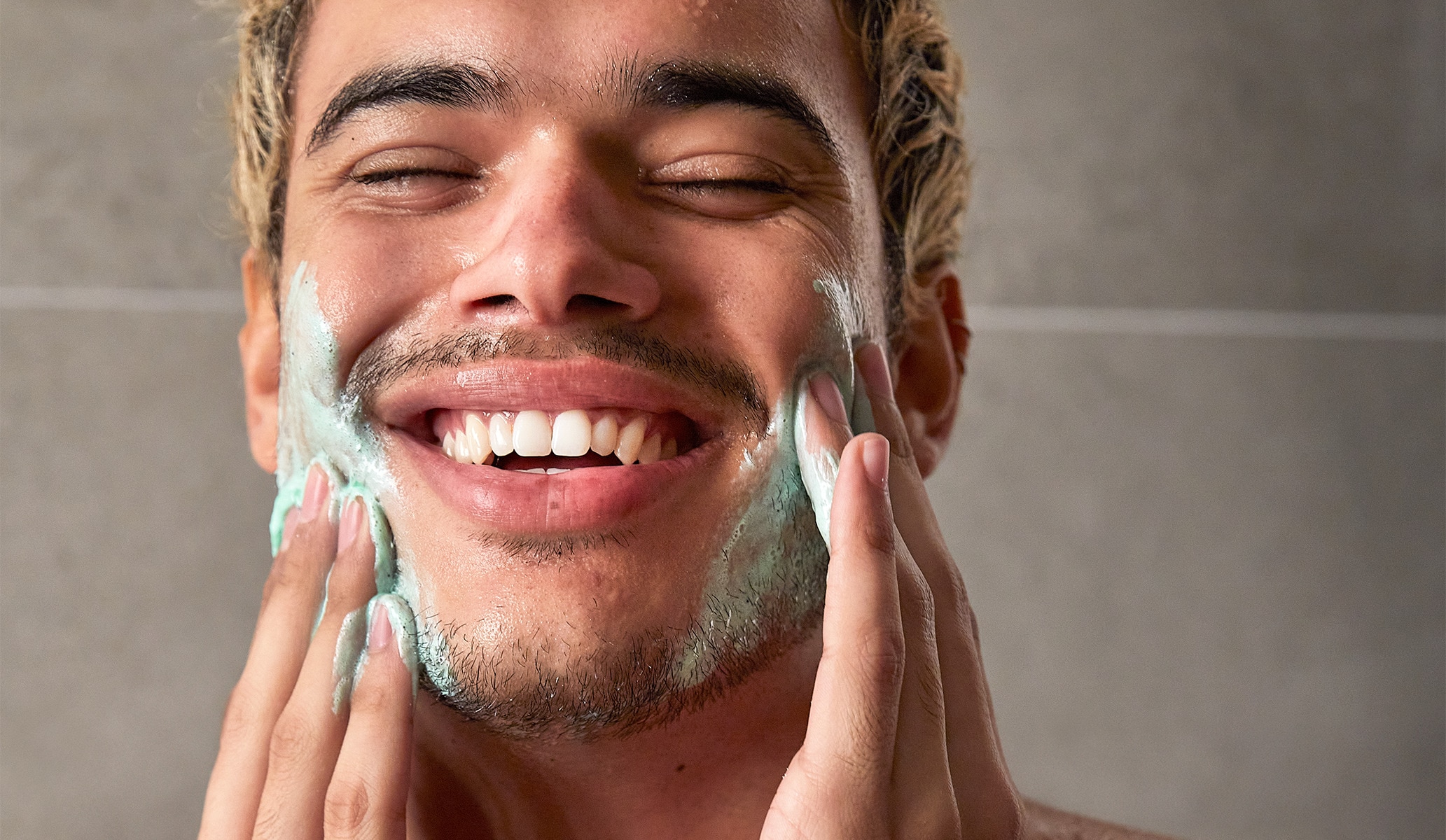 Smiling man lathering a foamy product on his face