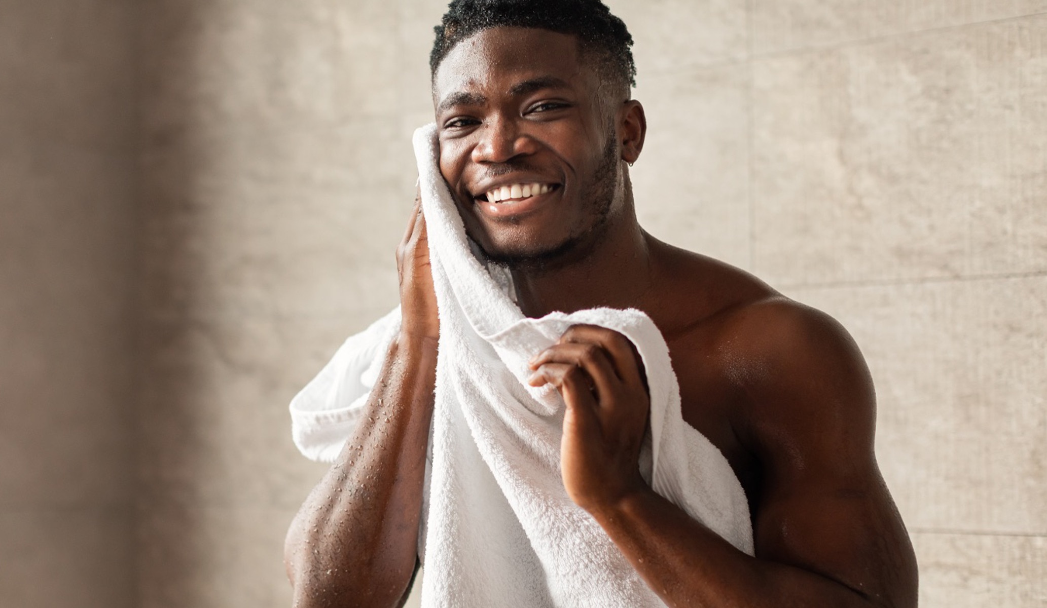 Man smiling and drying his face on a towel