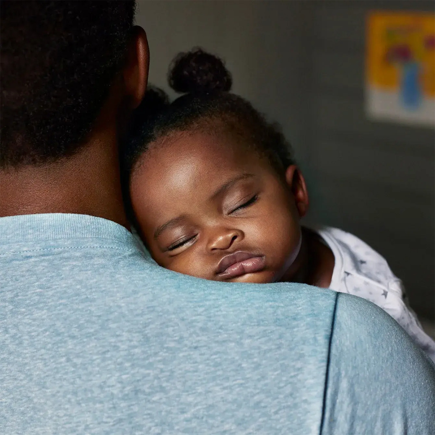 Image of a baby asleep over their father's shoulder