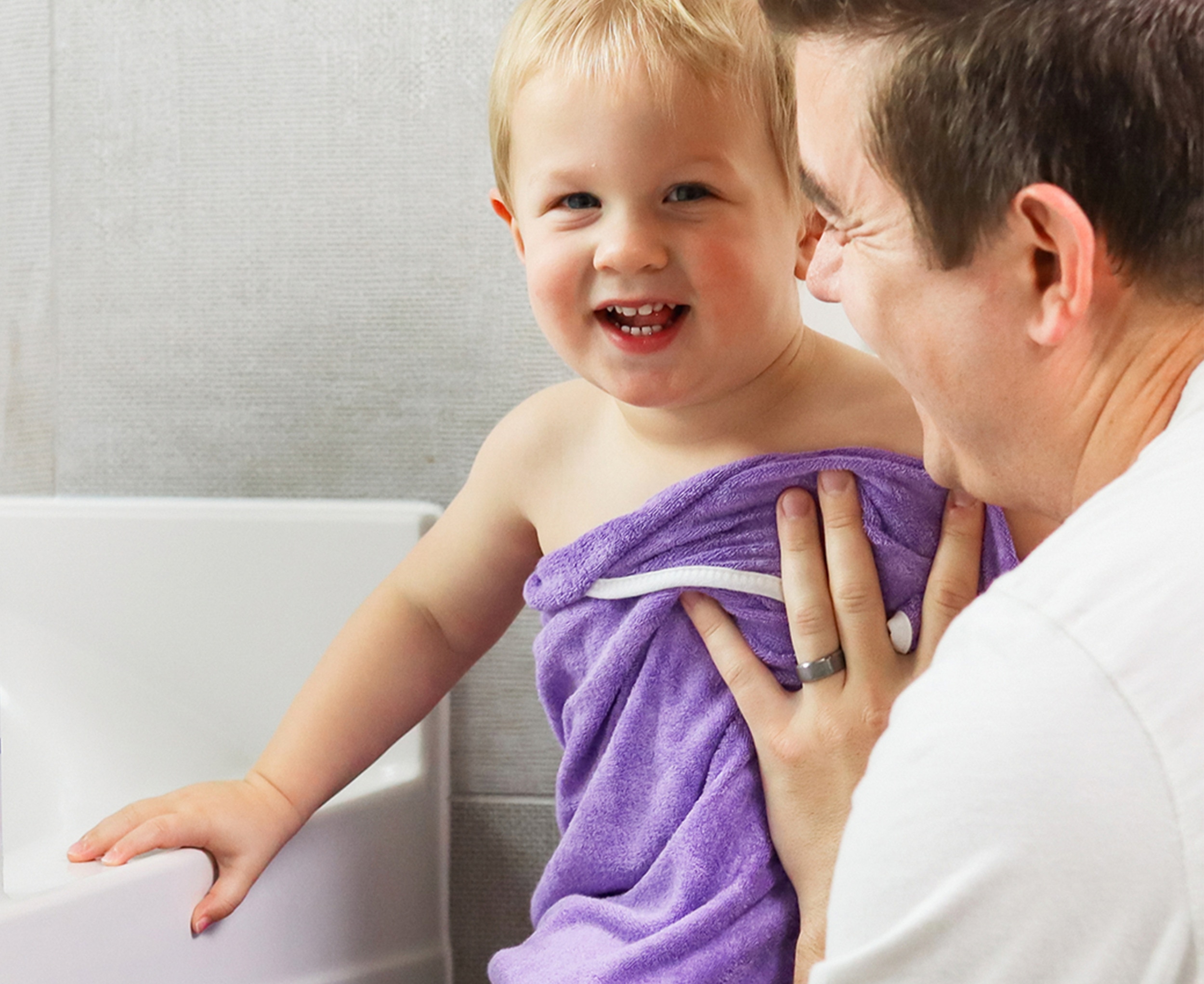 Man drying a baby with a purple towel