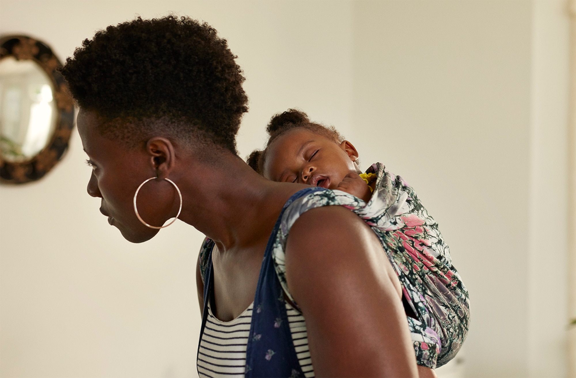 Image of a mother carrying her baby on her back in a sling