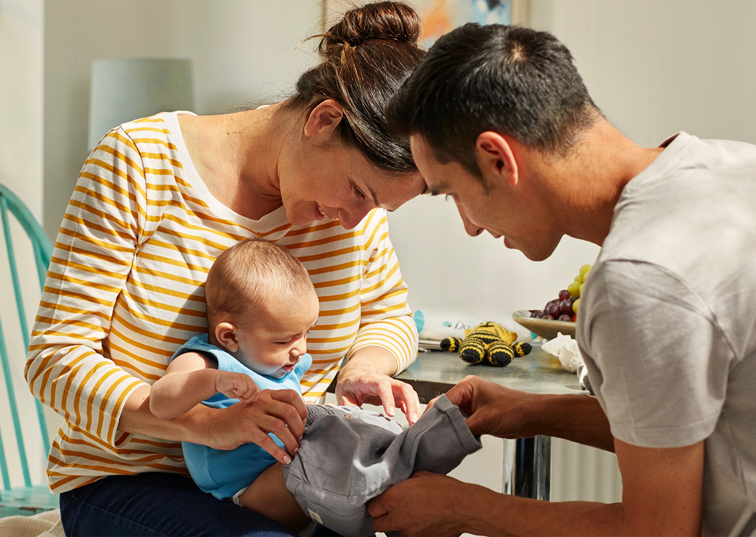 Image of a mother and father dressing their baby