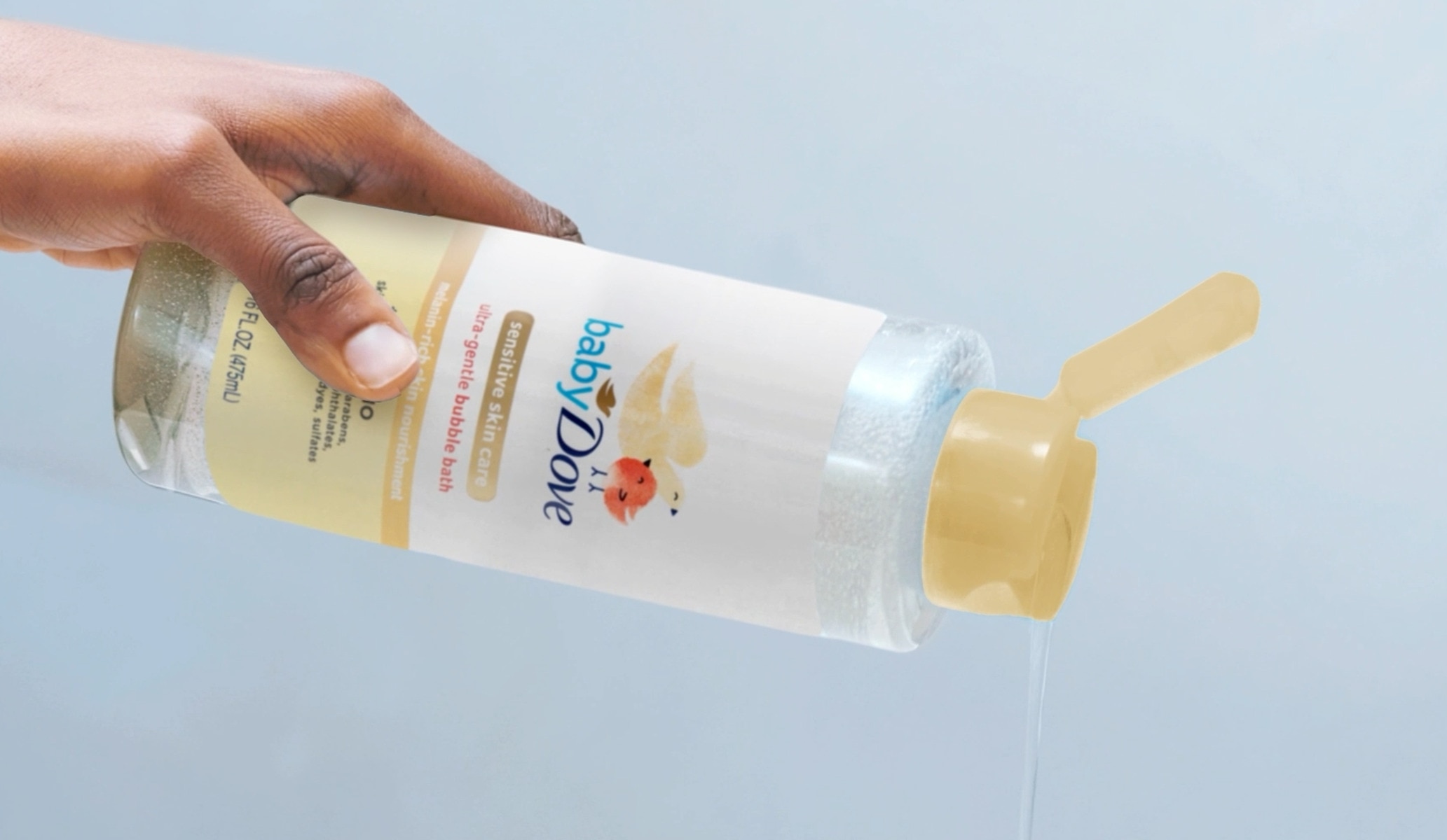 Hand pouring a Baby Dove bath product against a gray background