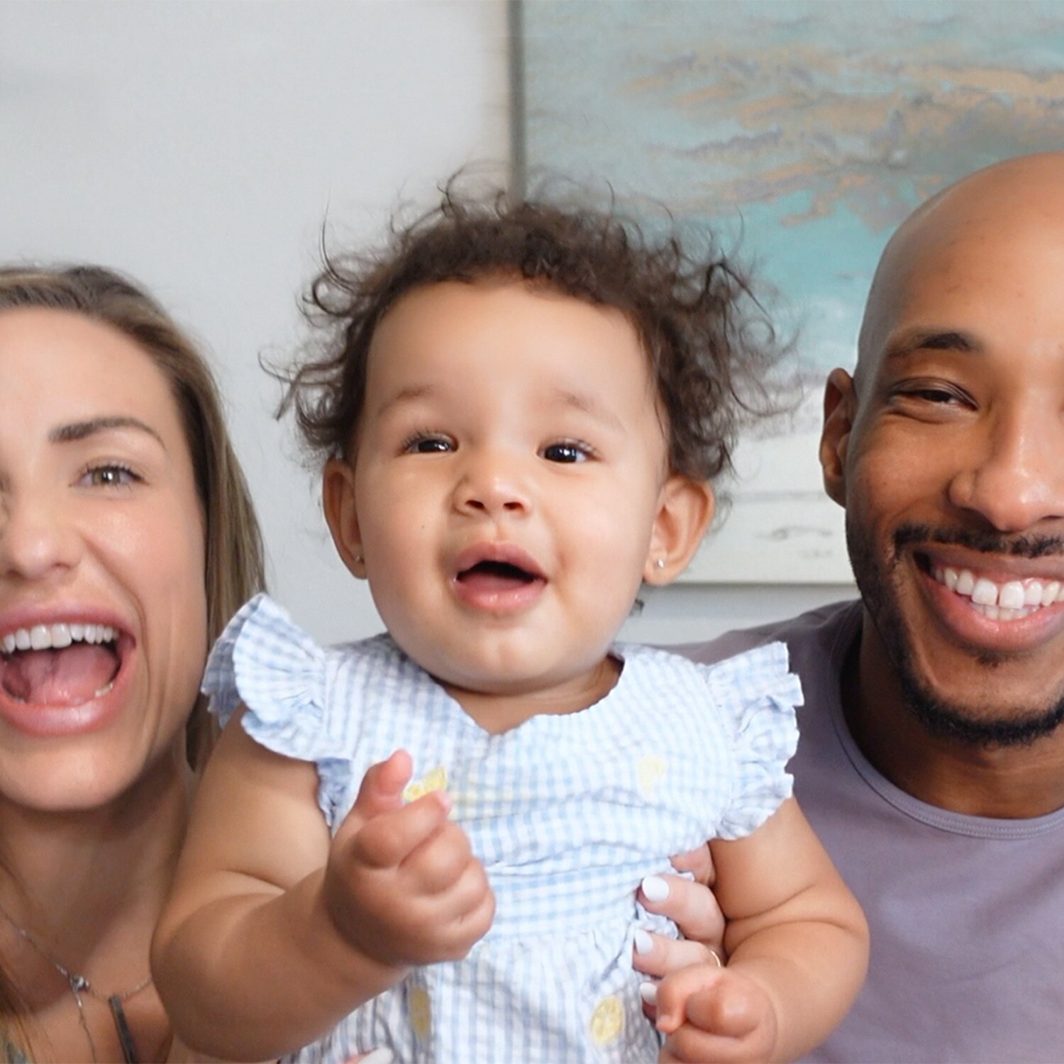 Baby sitting between their parents. All of them are smiling