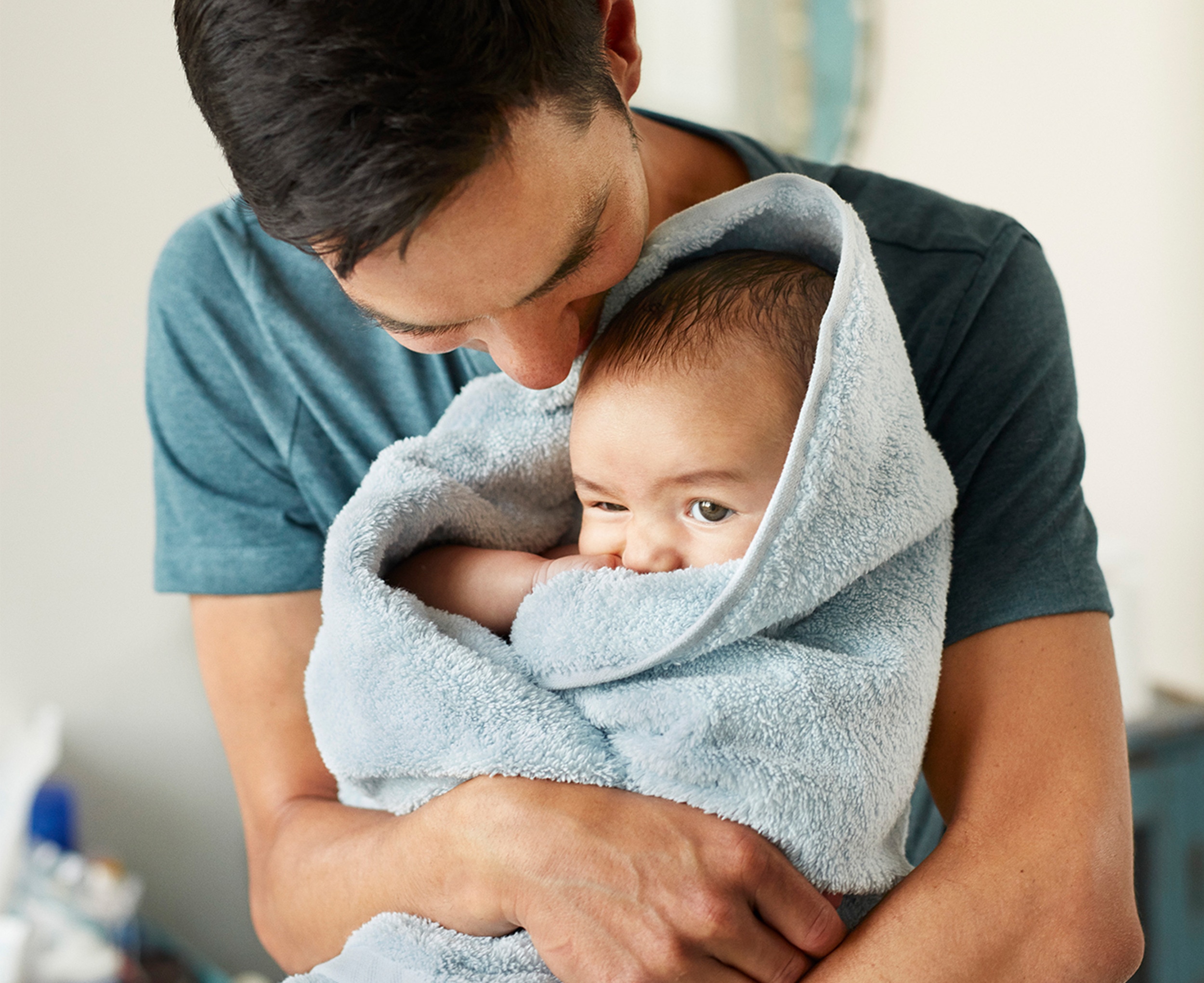 Man cuddling a baby wrapped in a towel