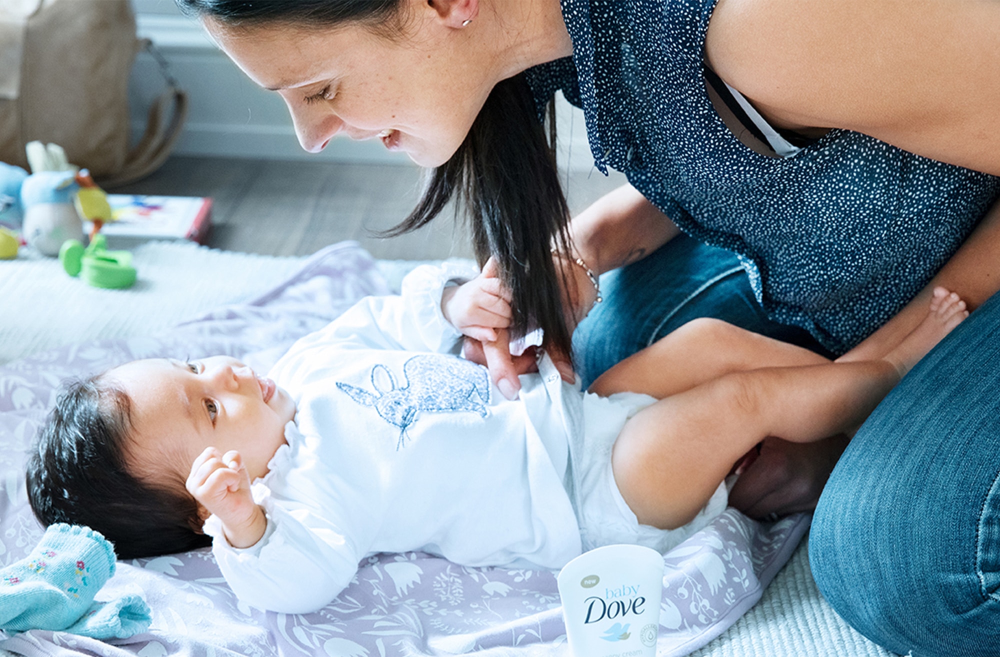 Mother talking to her baby who is lying on a blanket