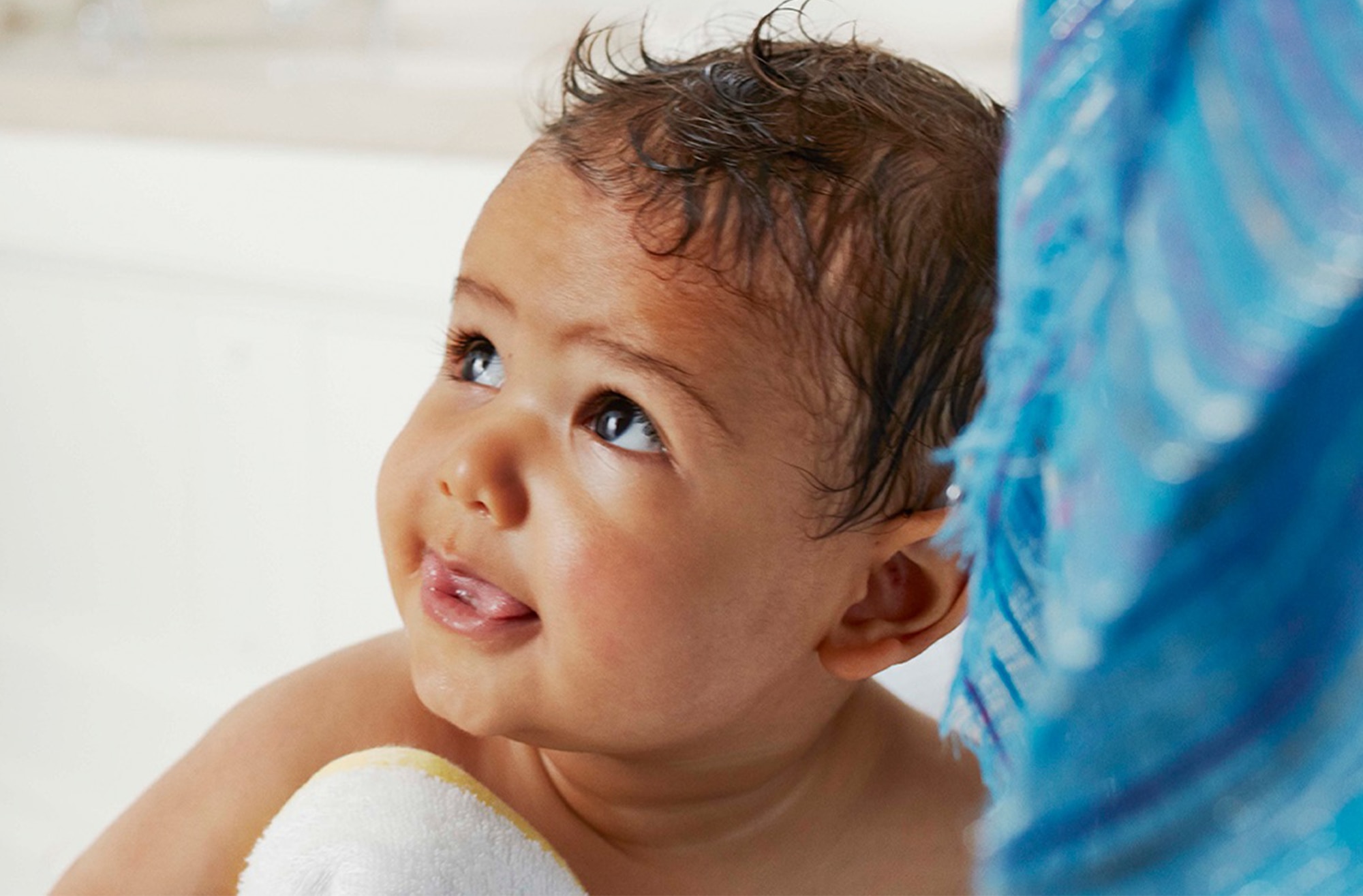 Image of a baby wrapped in a towel, looking up past the camera