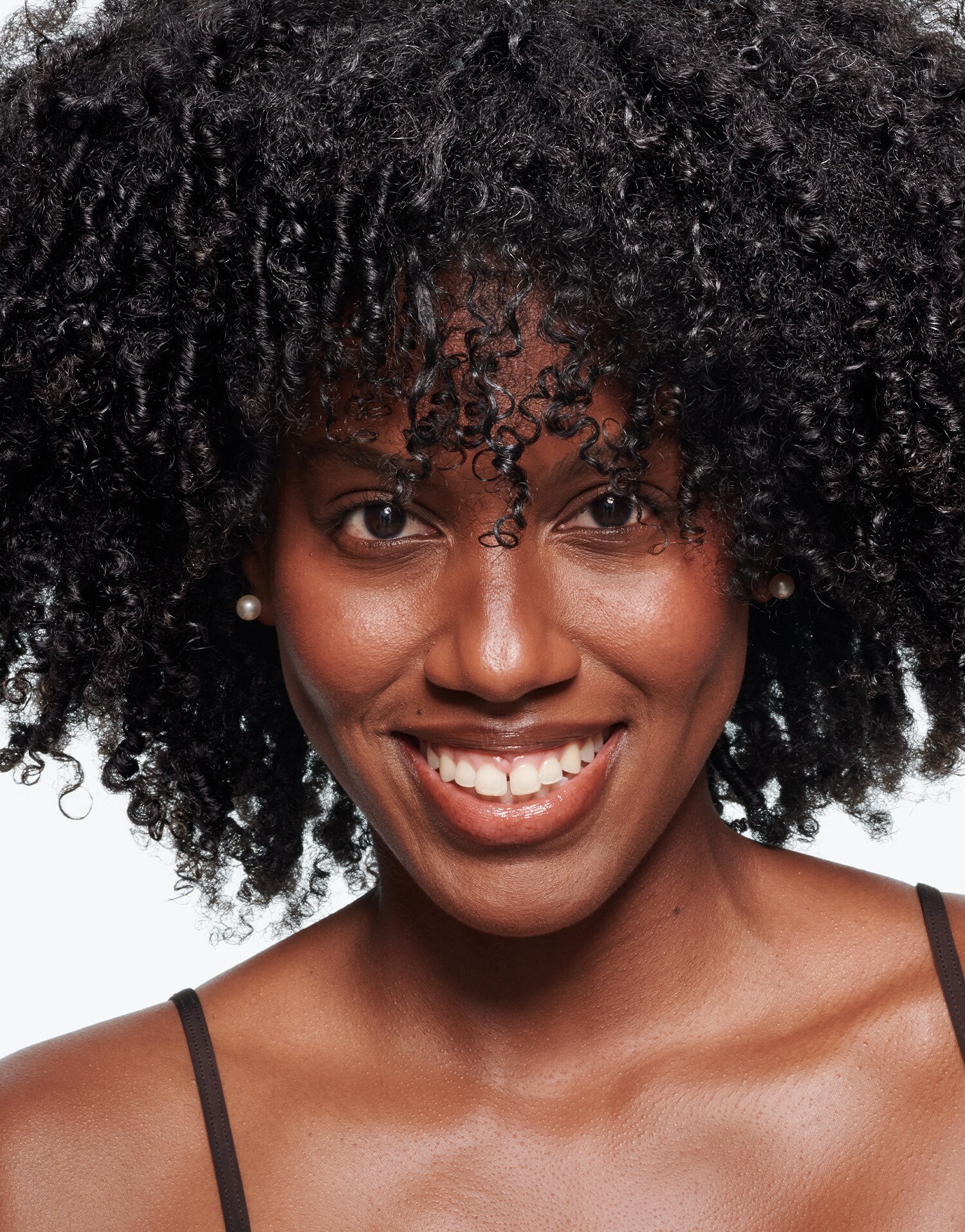 A woman with curly black hair smiles at the camera