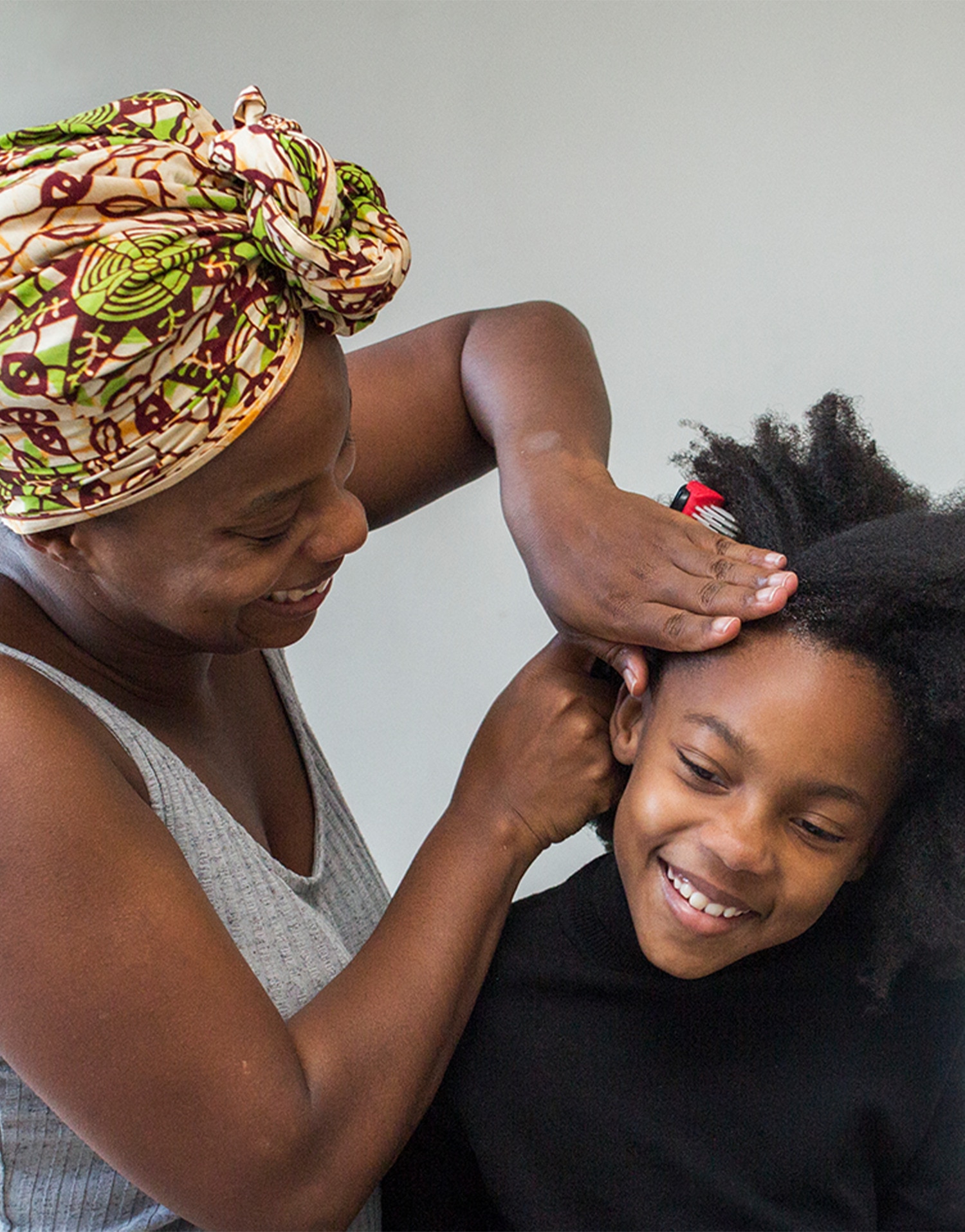 A woman styles a younger person's hair