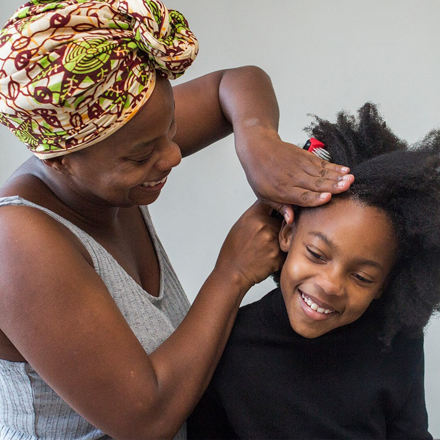 A woman styles a younger person's hair