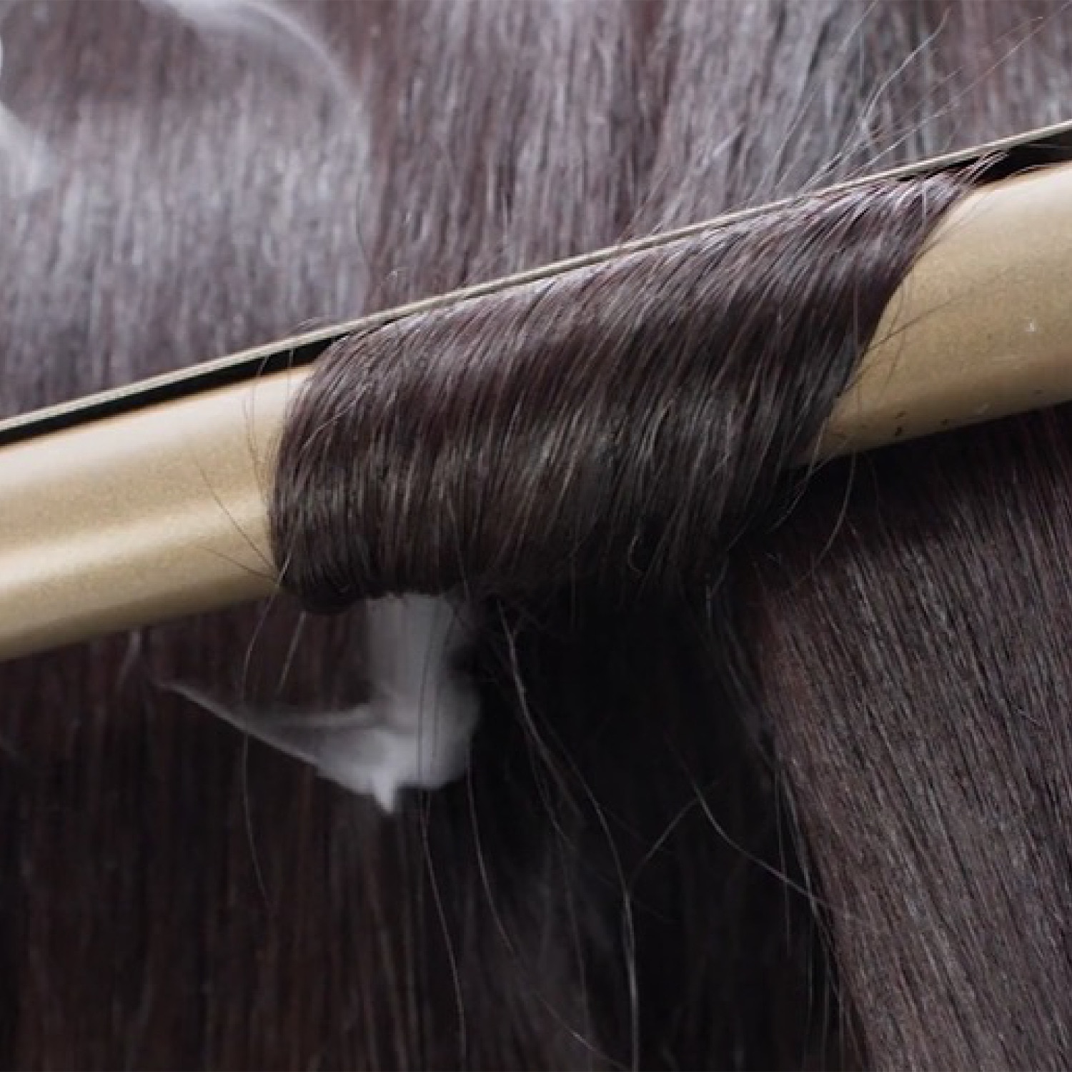 Close-up shot of long black hait being straightened