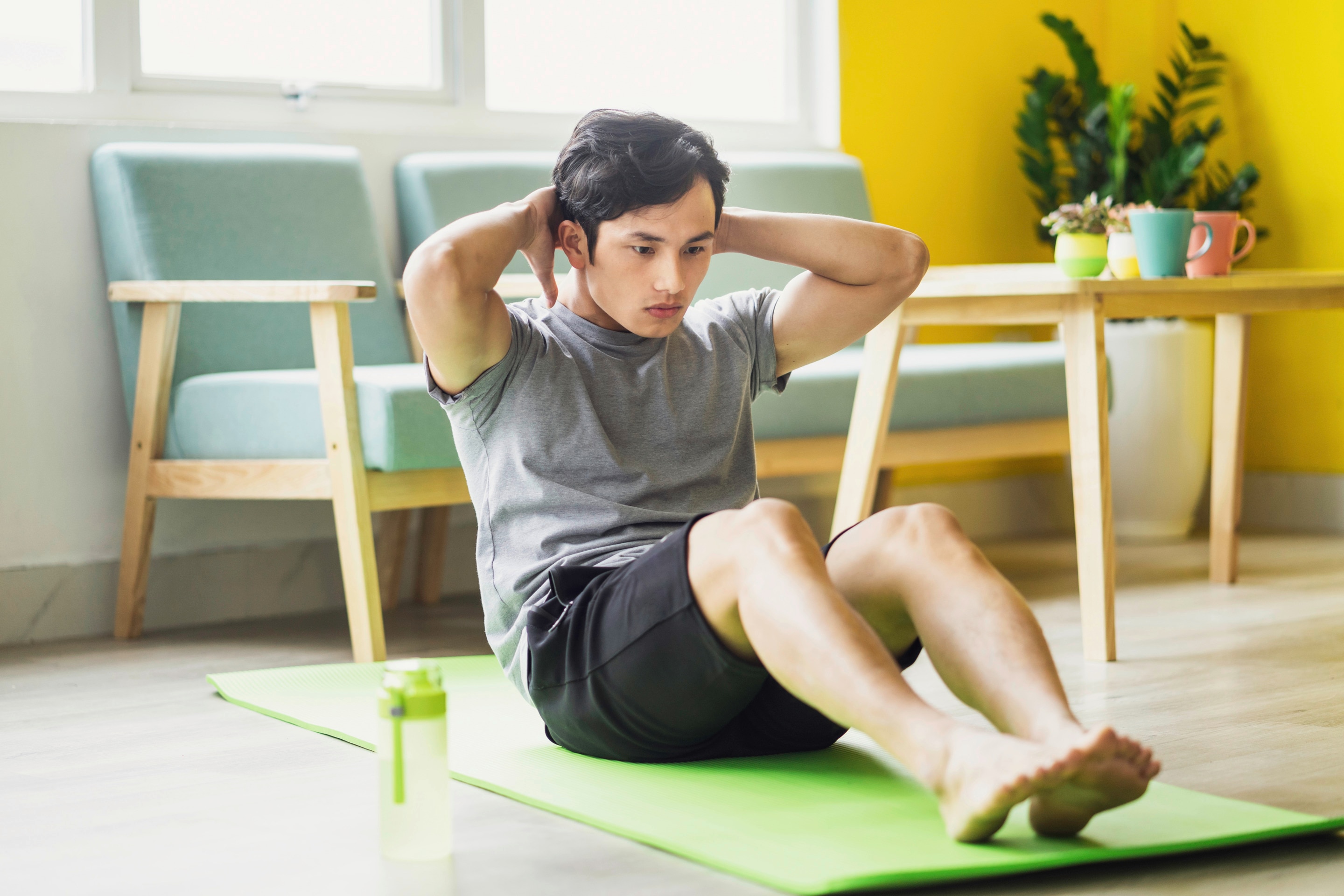 Pria sedang melakukan olahraga sit up di rumah.