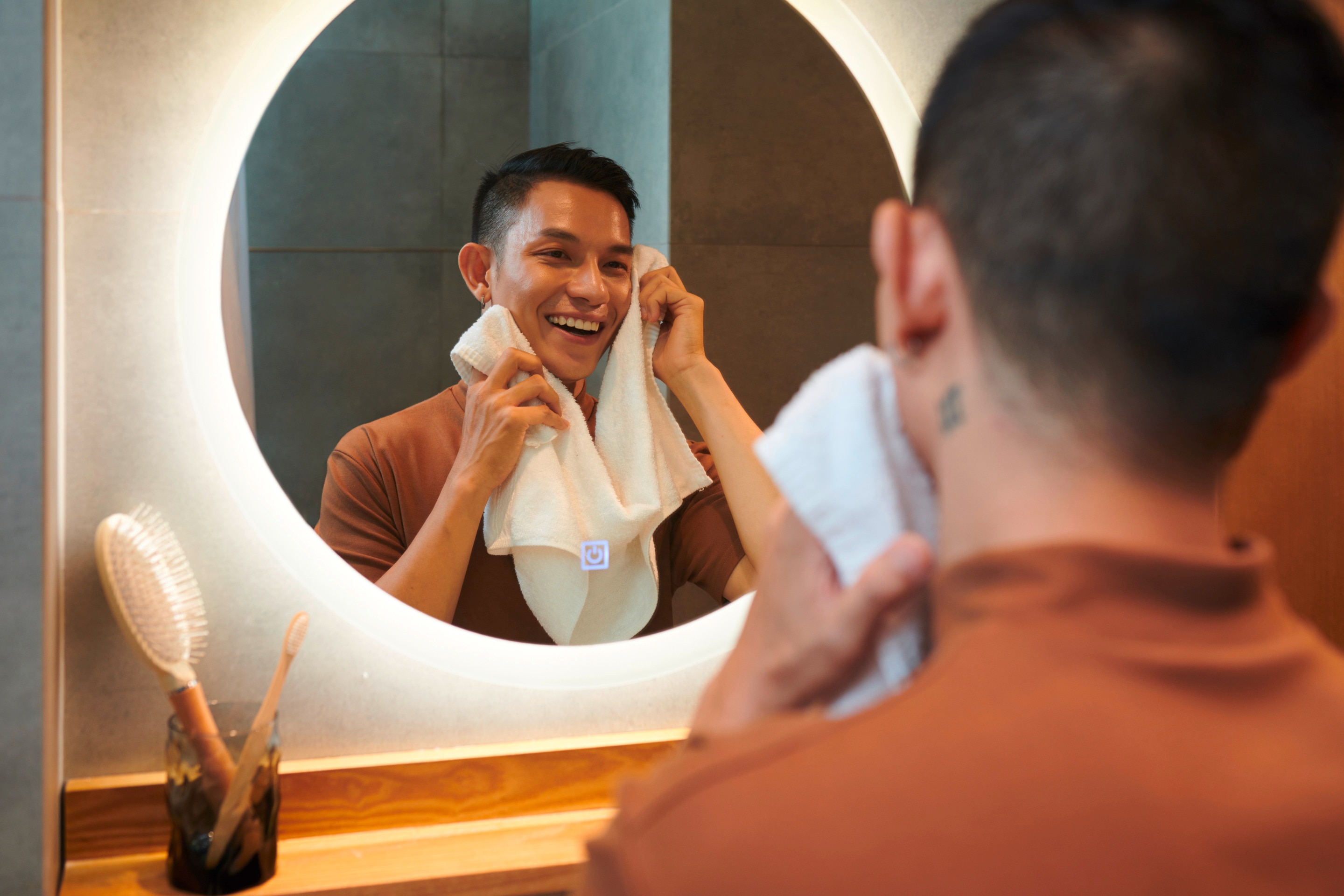 An Asian man wiping his face with a towel.
