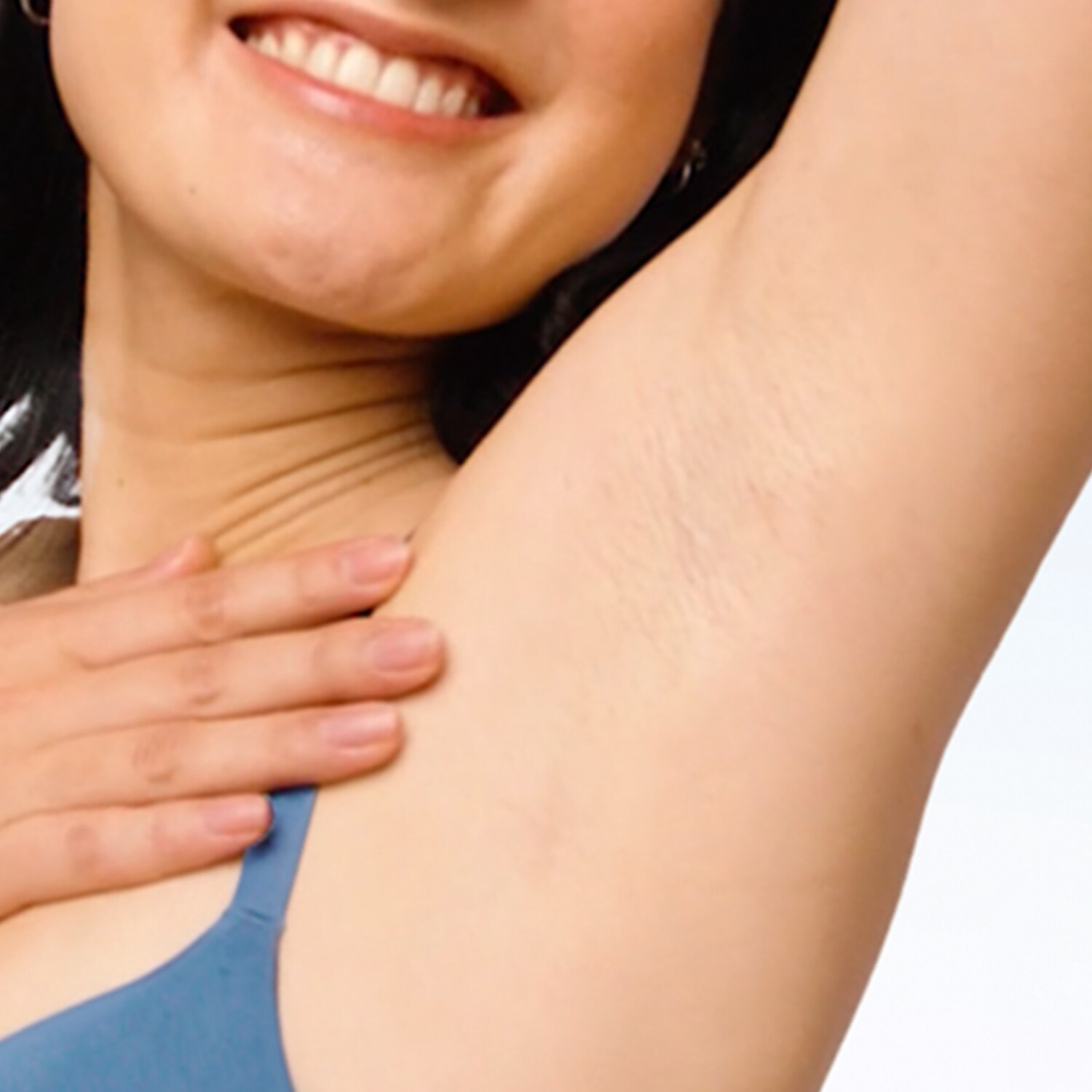 Smiling woman with arm raised and one hand touching her underarm