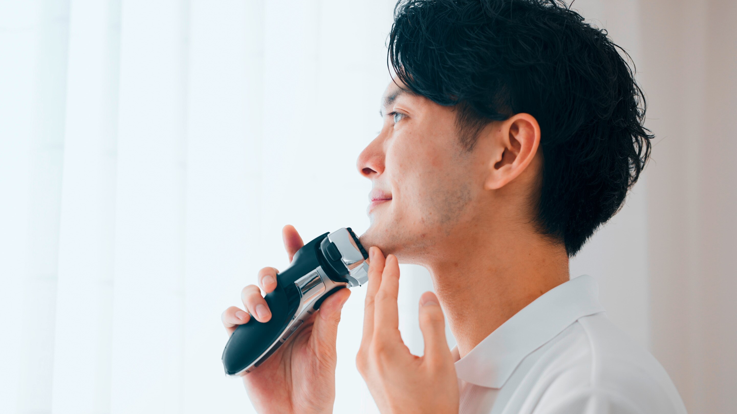 Man grooming with an electric shaver.