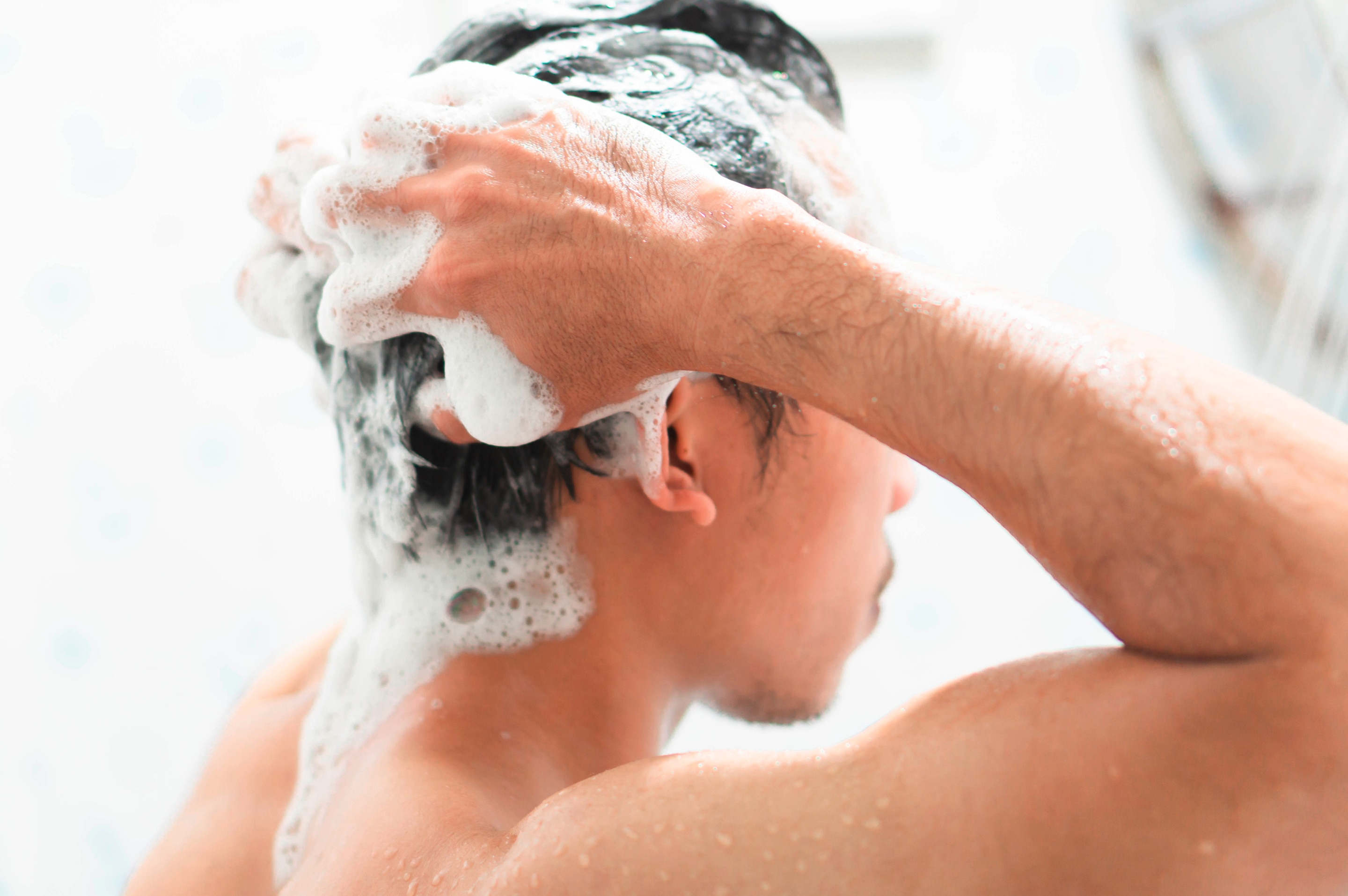 A man washes his hair with shampoo.