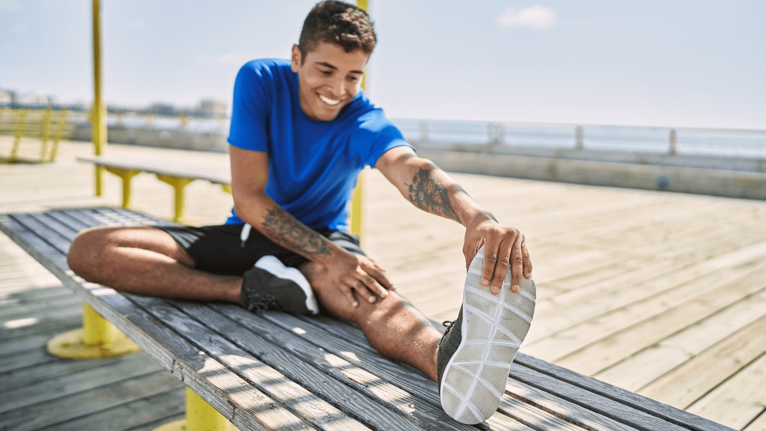 Young man stretching while holding onto his sweaty shoes 