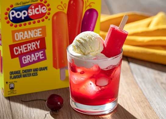 Popsicle Cherry Ice Pop floats in a glass with a scoop of vanilla ice cream