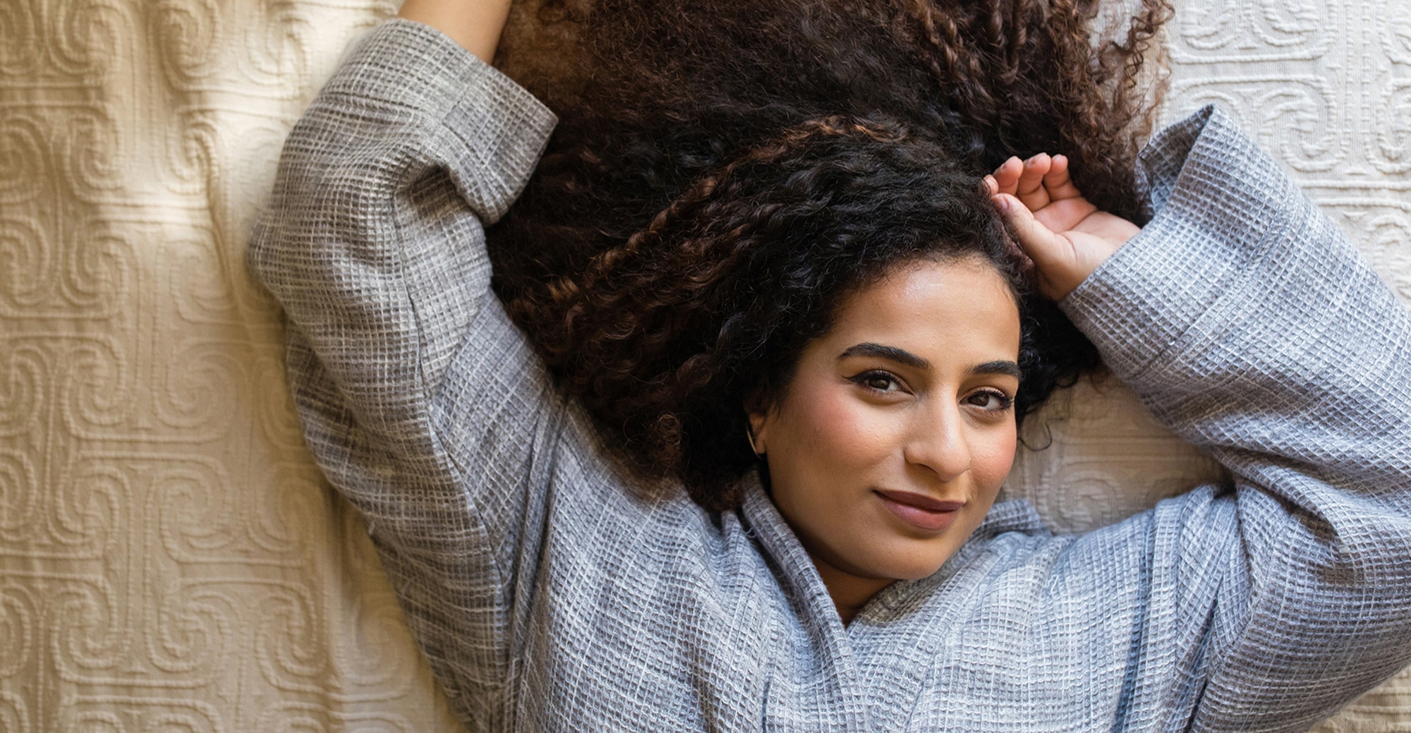 A lady lays on her back, facing the camera
