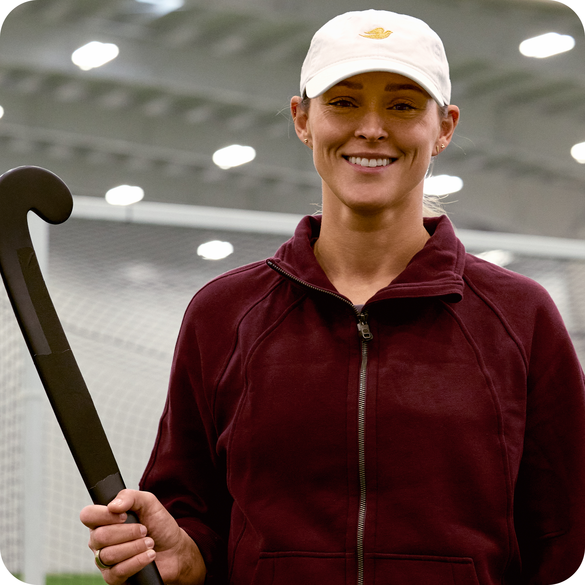 Kylie Kelce smiling whilst holding a field hockey stick