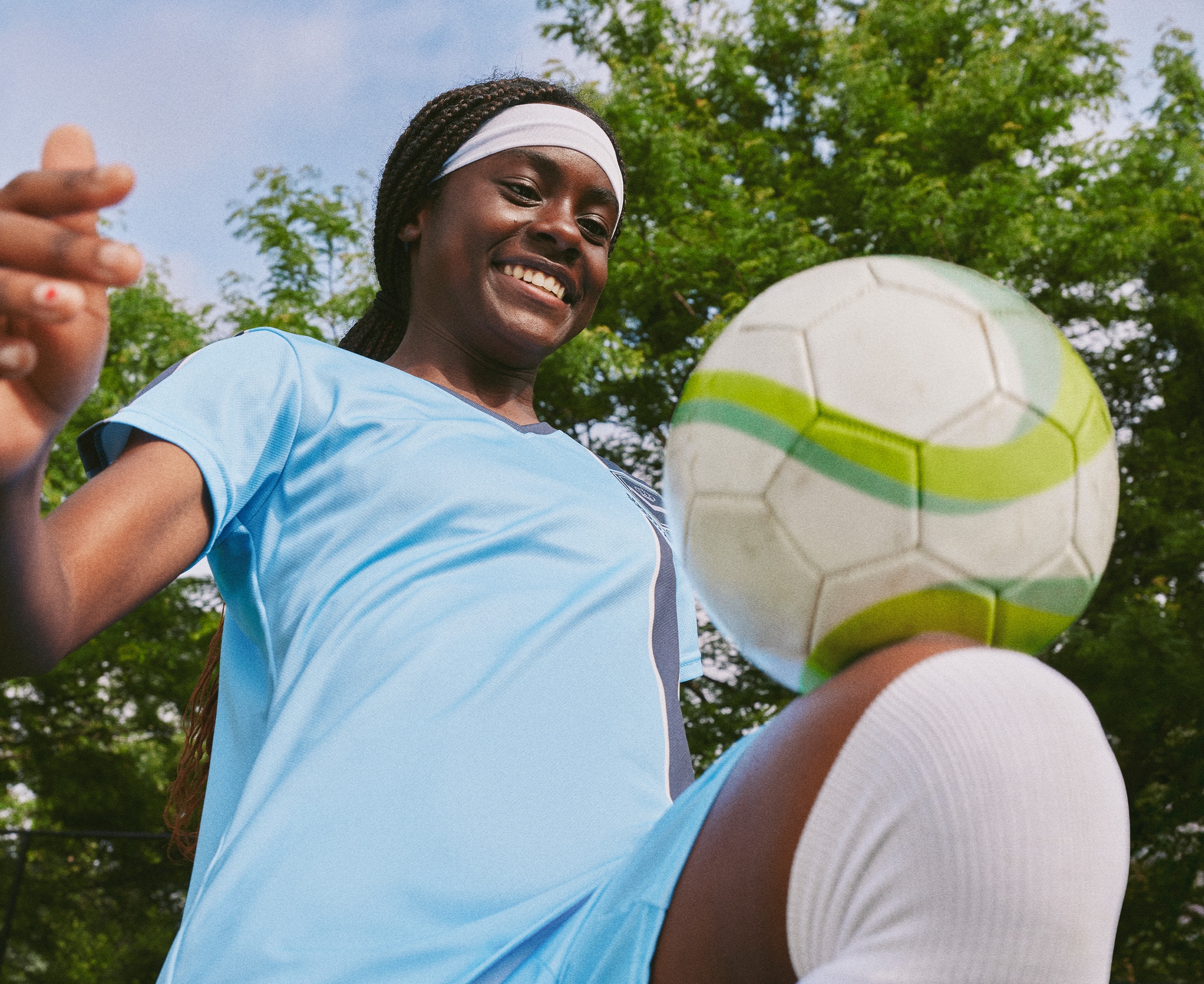 Girl smiling whilst knee-ups with a football