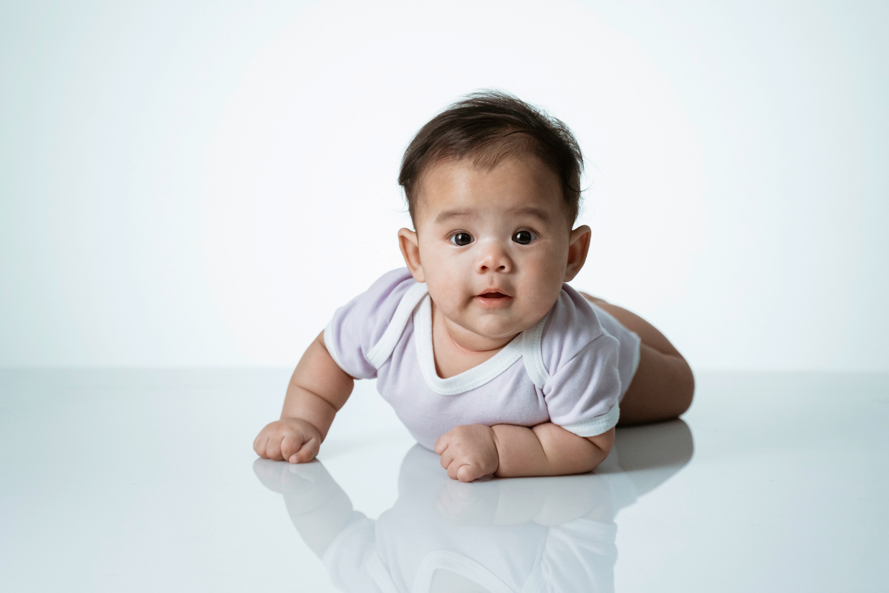 bayi melakukan tummy time di atas permukaan datar untuk melatih kekuatan otot dan leher.