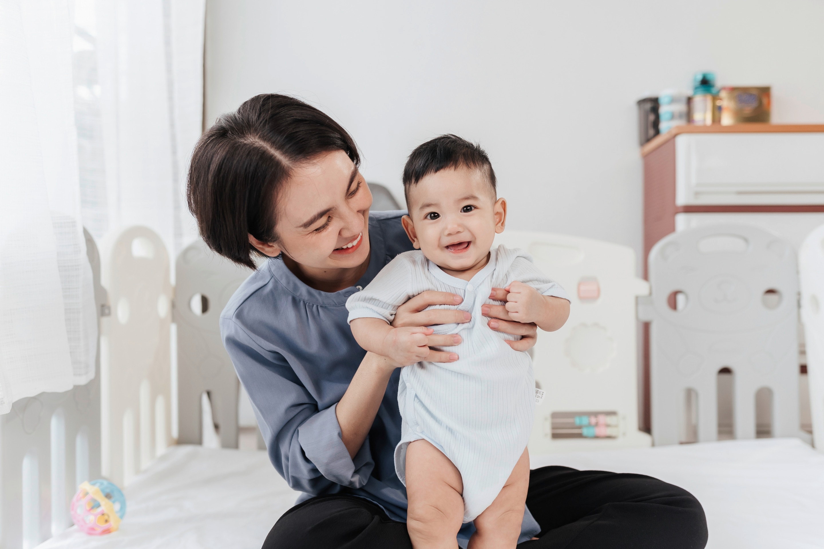 seorang ibu sedang memeluk bayi berusia 5 bulan.