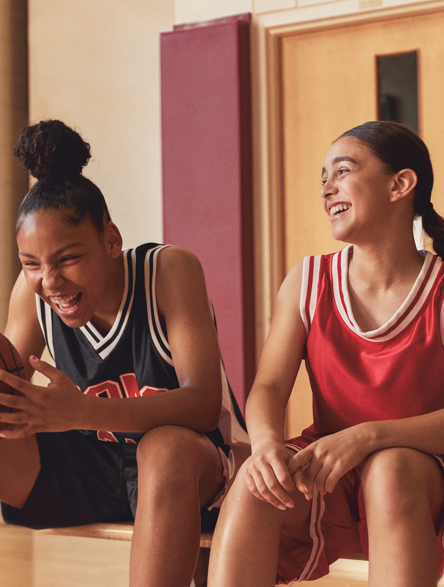 Girl smiling holding a football between her feet on a football field