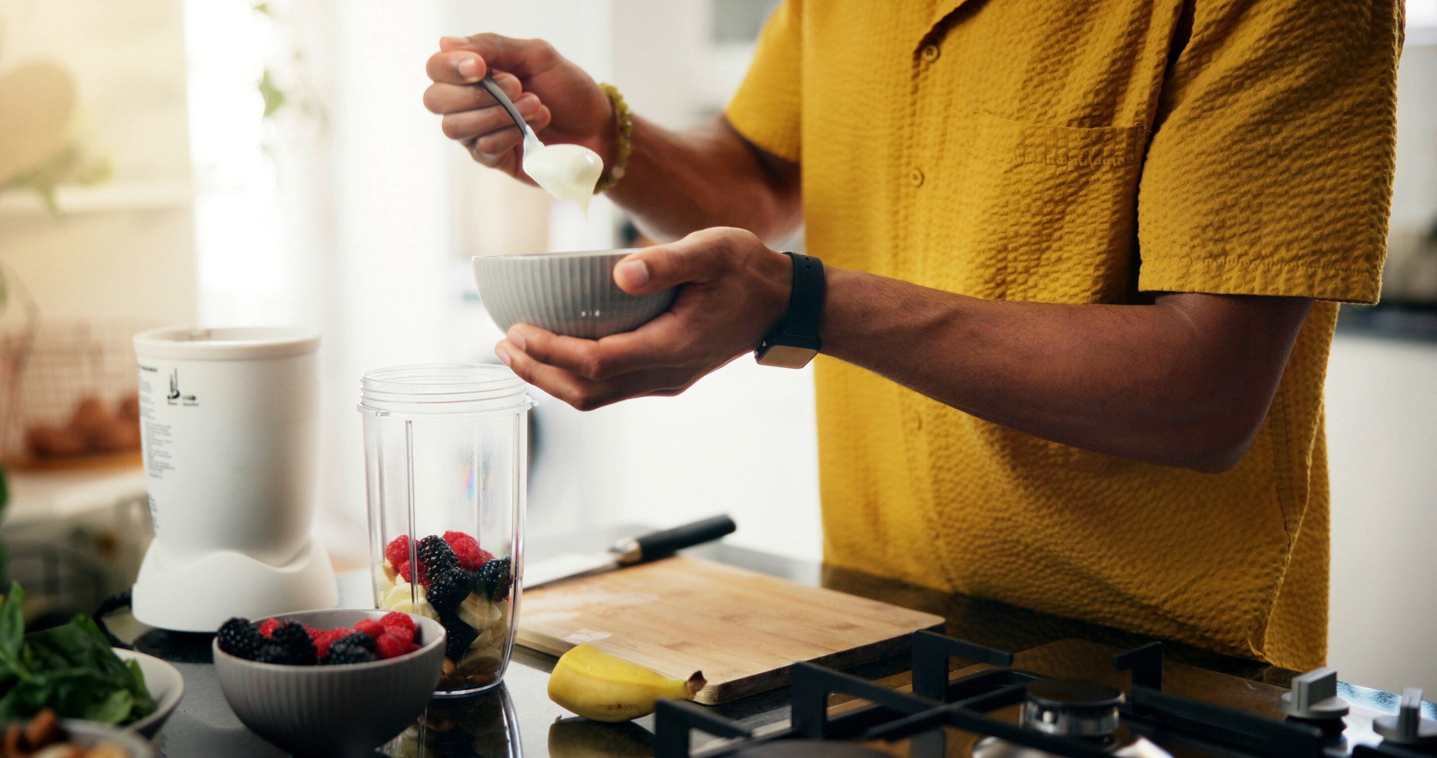 A man prepares the ingredients for a smoothie bowl in his kitchen.