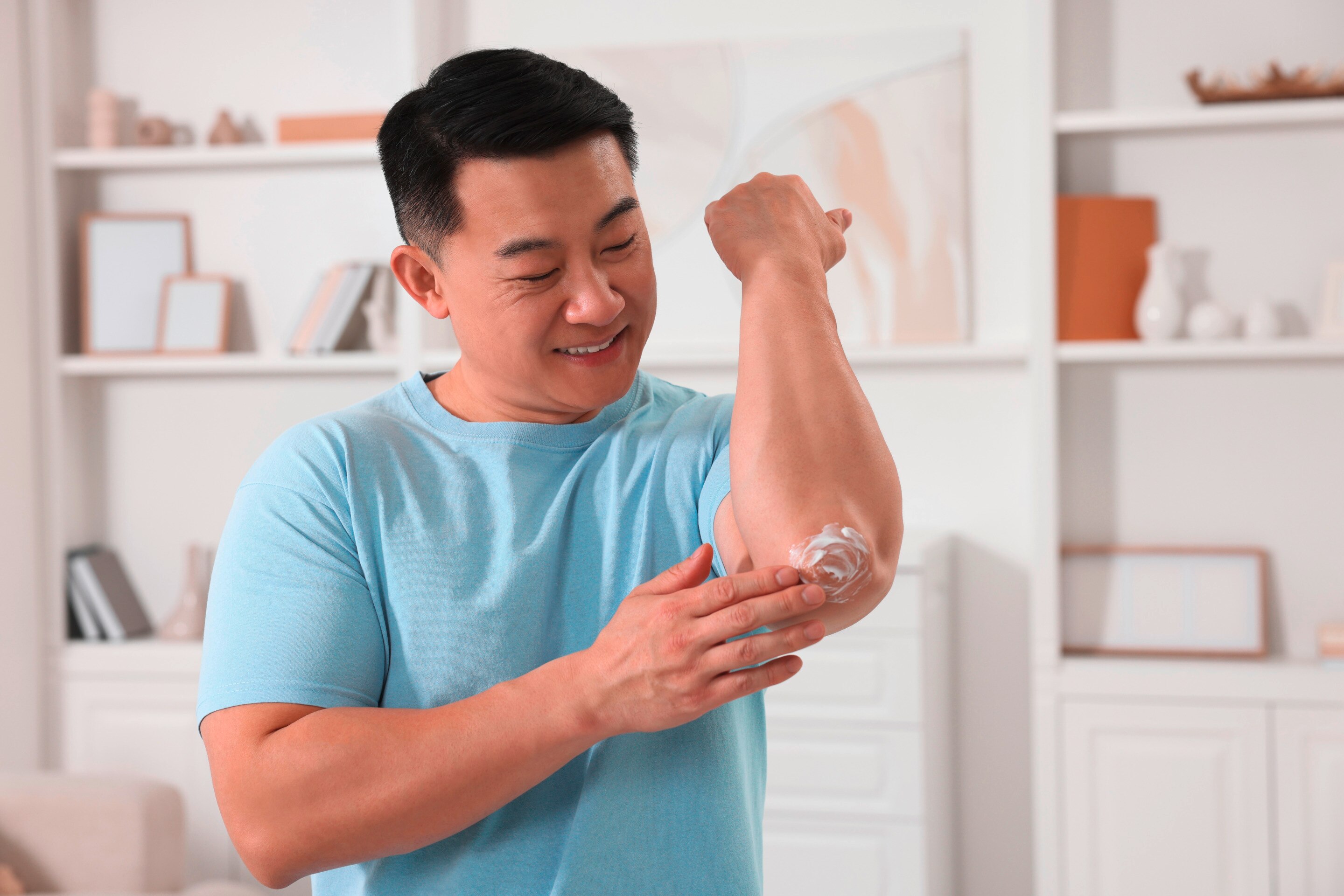 Man putting lotion on his elbows.