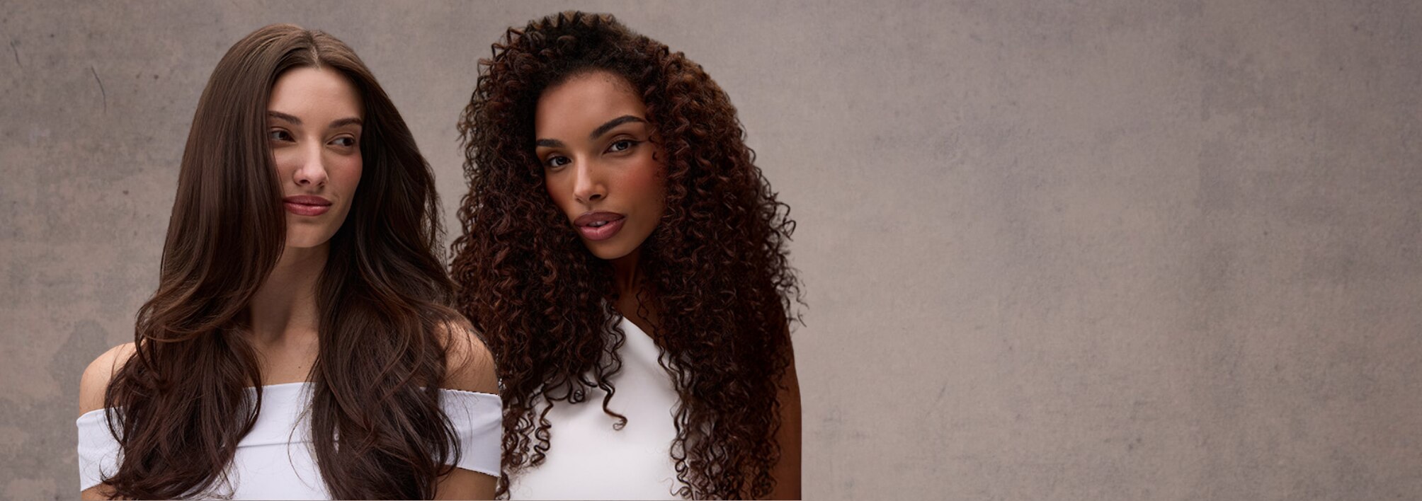 Two individuals with beautifully styled hair, highlighting contrasting textures. One has long, smooth, and shiny waves, while the other features defined, voluminous curls.