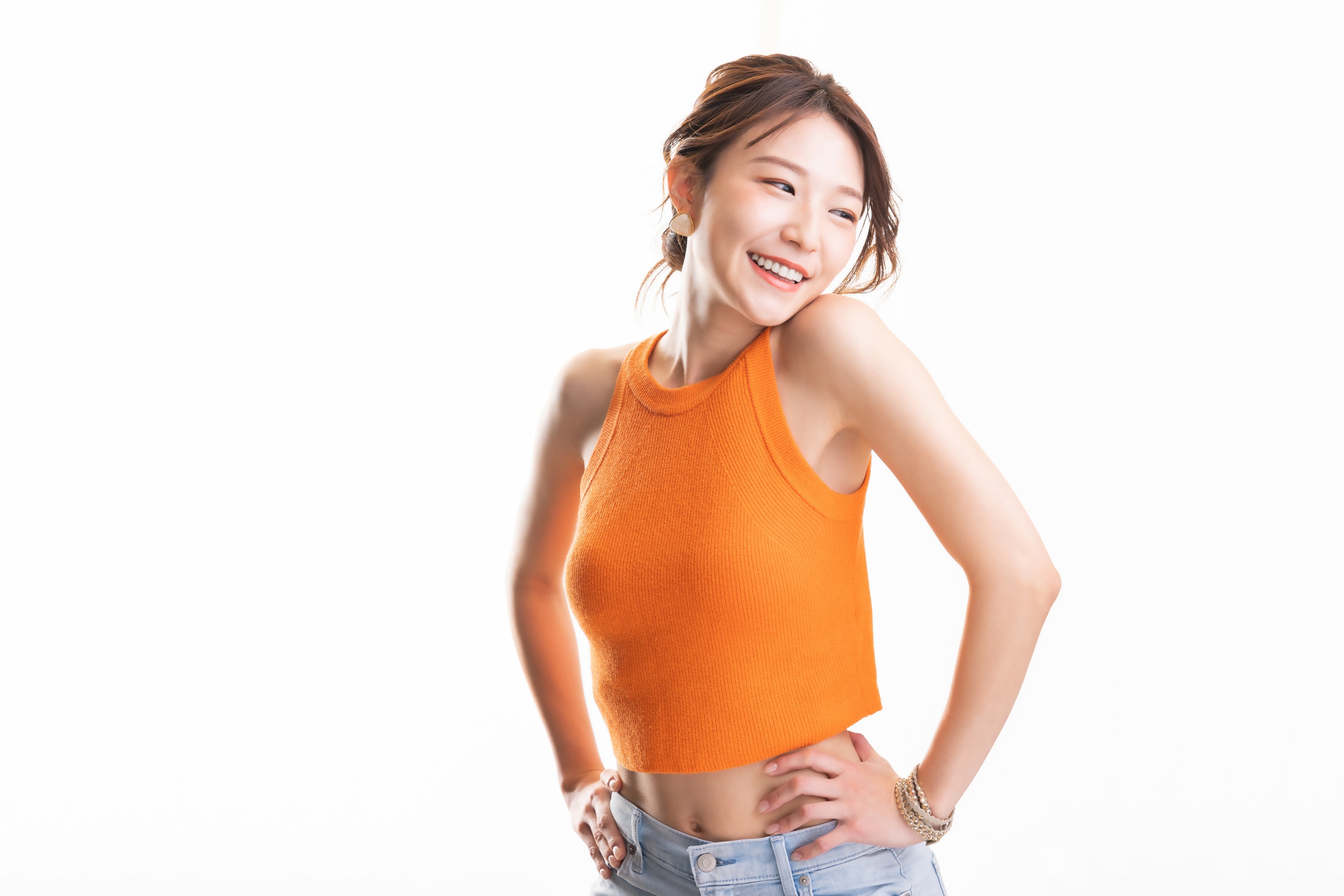 ada wanita yang mengenakan baju oranye tanpa lengan, tersenyum percaya diri sambil memperlihatkan area ketiak yang tampak bersih.