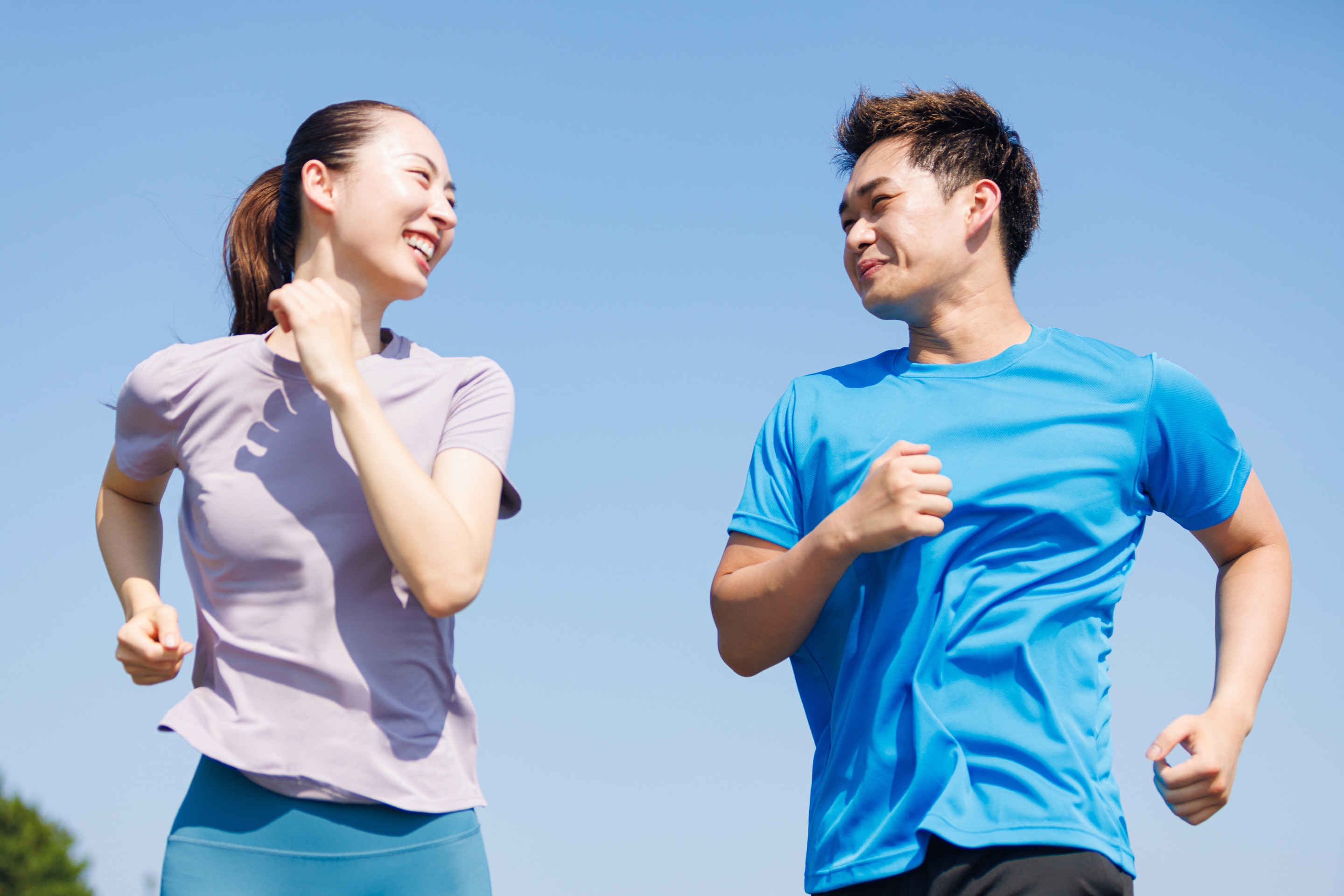 ada pria dan wanita berlari bersama di luar ruangan di bawah terik matahari