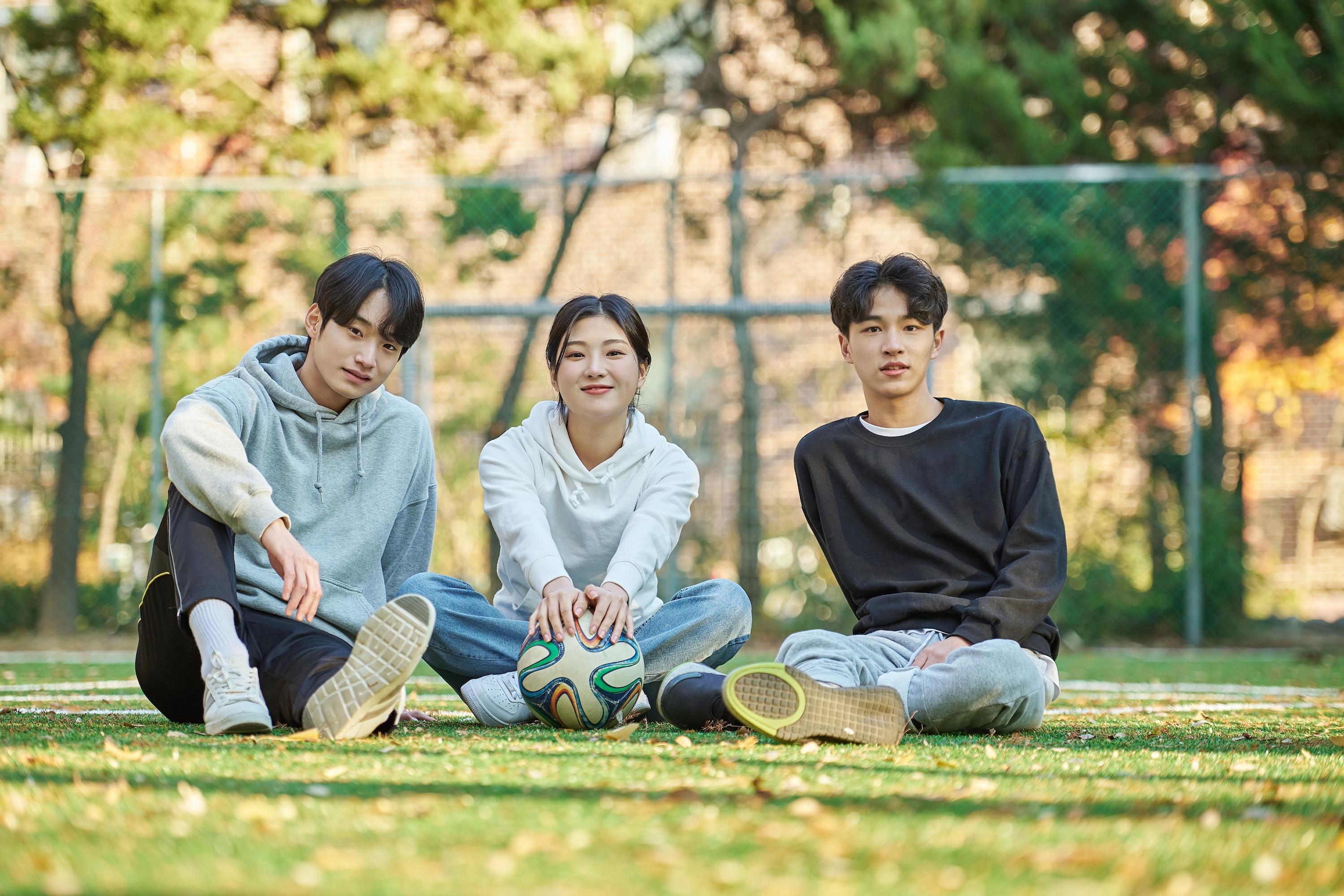 ada tiga remaja duduk di lapangan sekolah setelah olahraga.