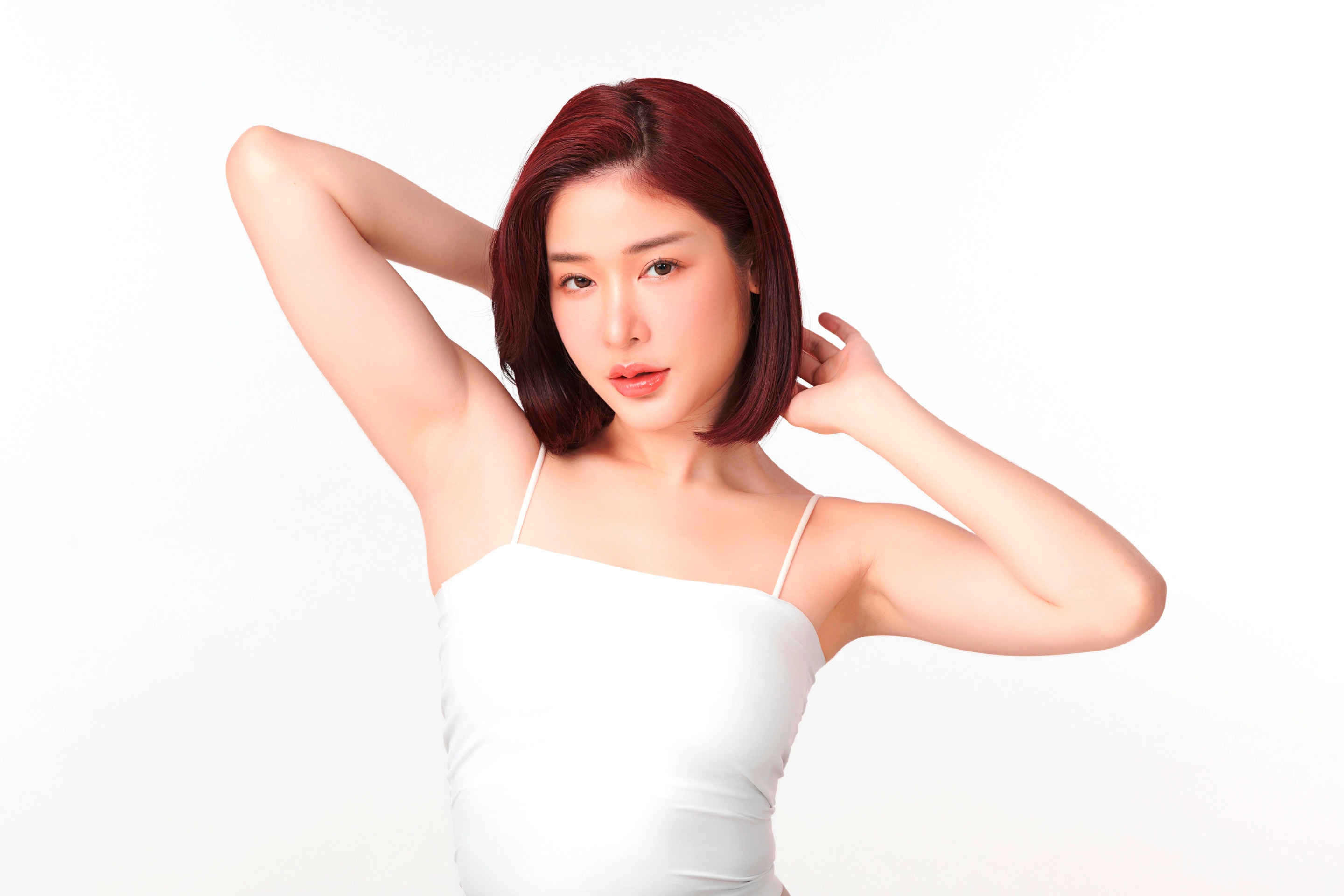 seorang wanita asia sedang mengangkat kedua tangannya untuk memperlihatkan area ketiak yang tampak bersih dan bebas dari bulu